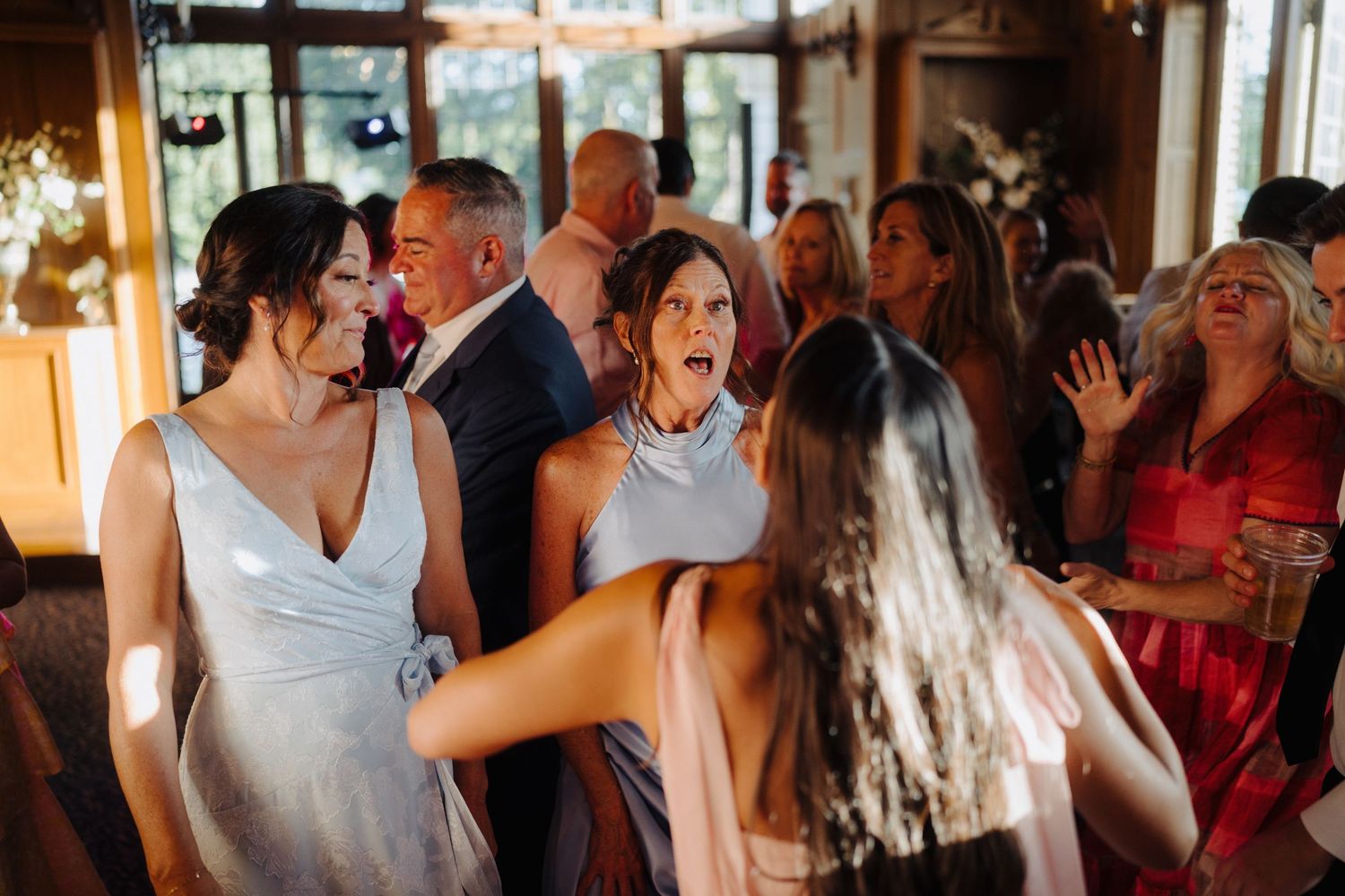 Wedding reception guests dancing and celebrating in an indoor venue.