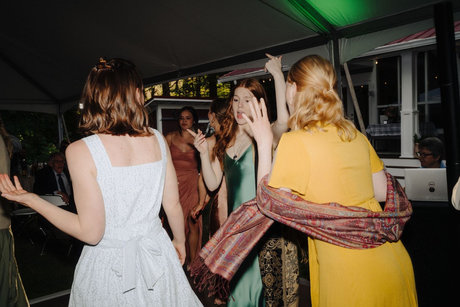Wedding reception dance party with colorful lighting and guests celebrating.