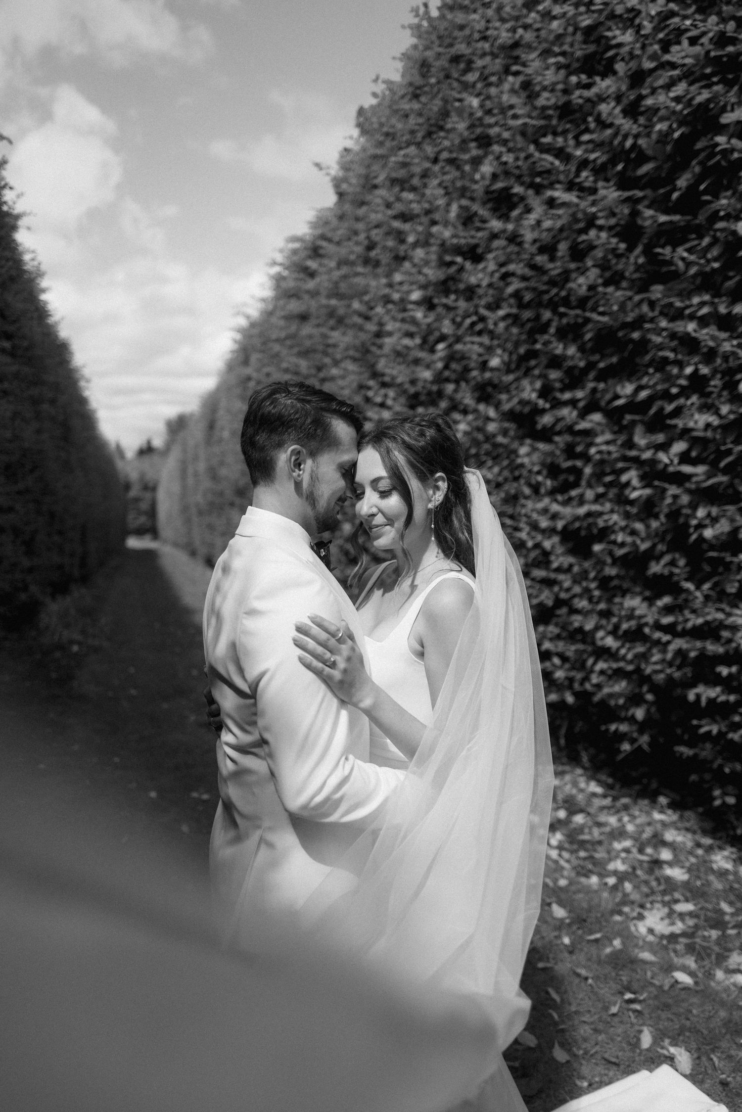 Black and white wedding portraits showing tender moments between newlyweds in a garden setting.