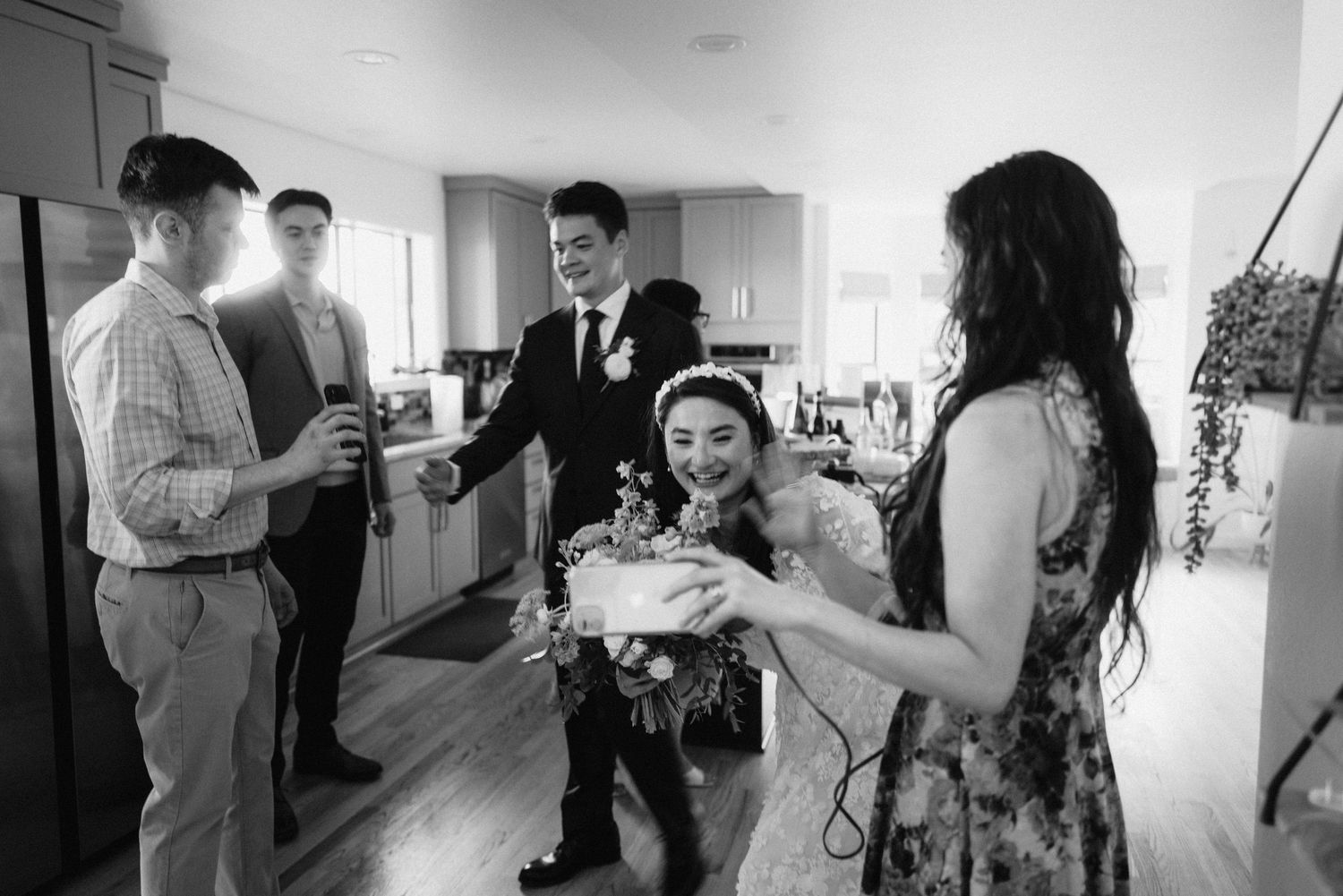 Wedding party members interact and prepare in a bright hallway setting.