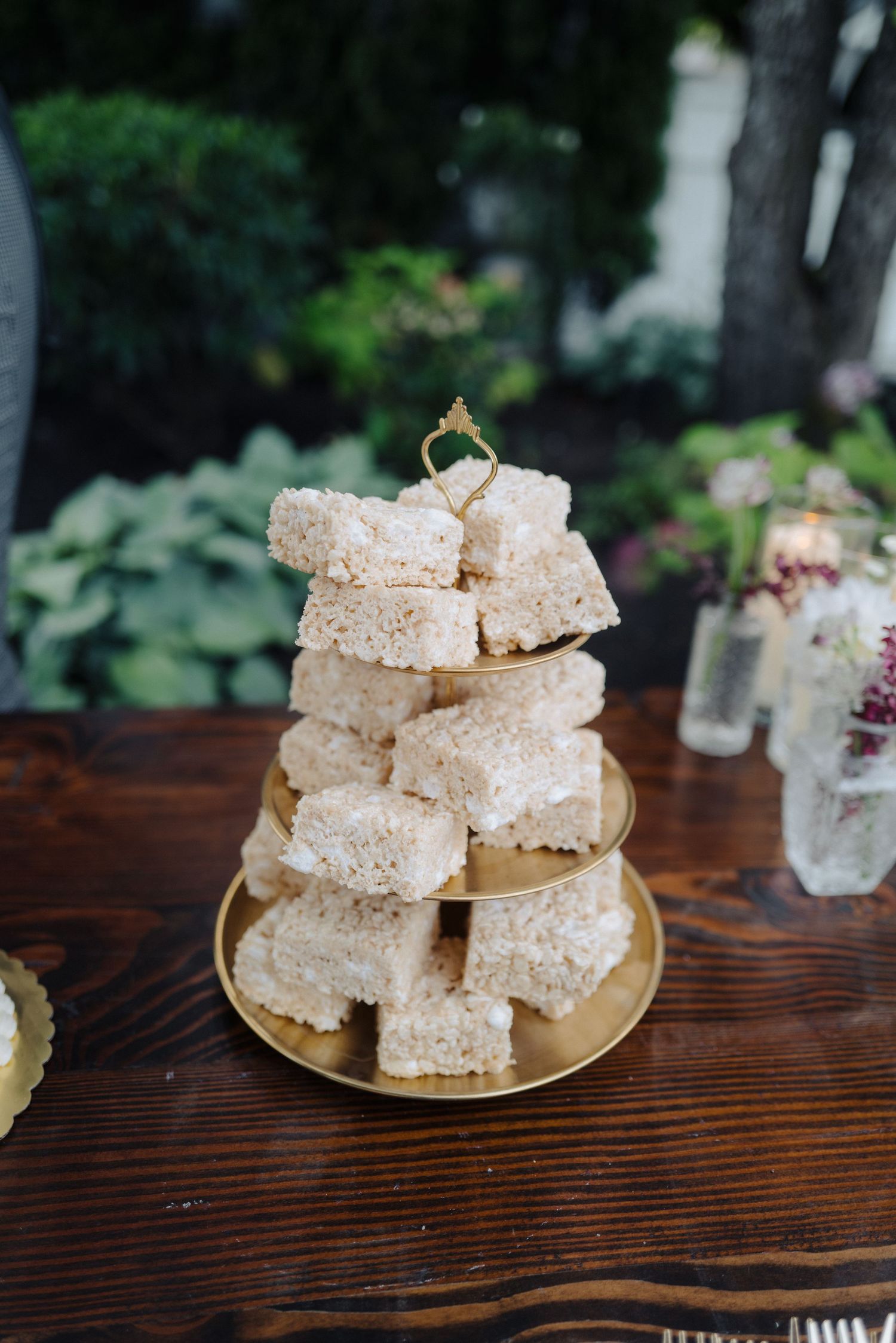 A tower of white rice krispy treats stacked on a golden plate.