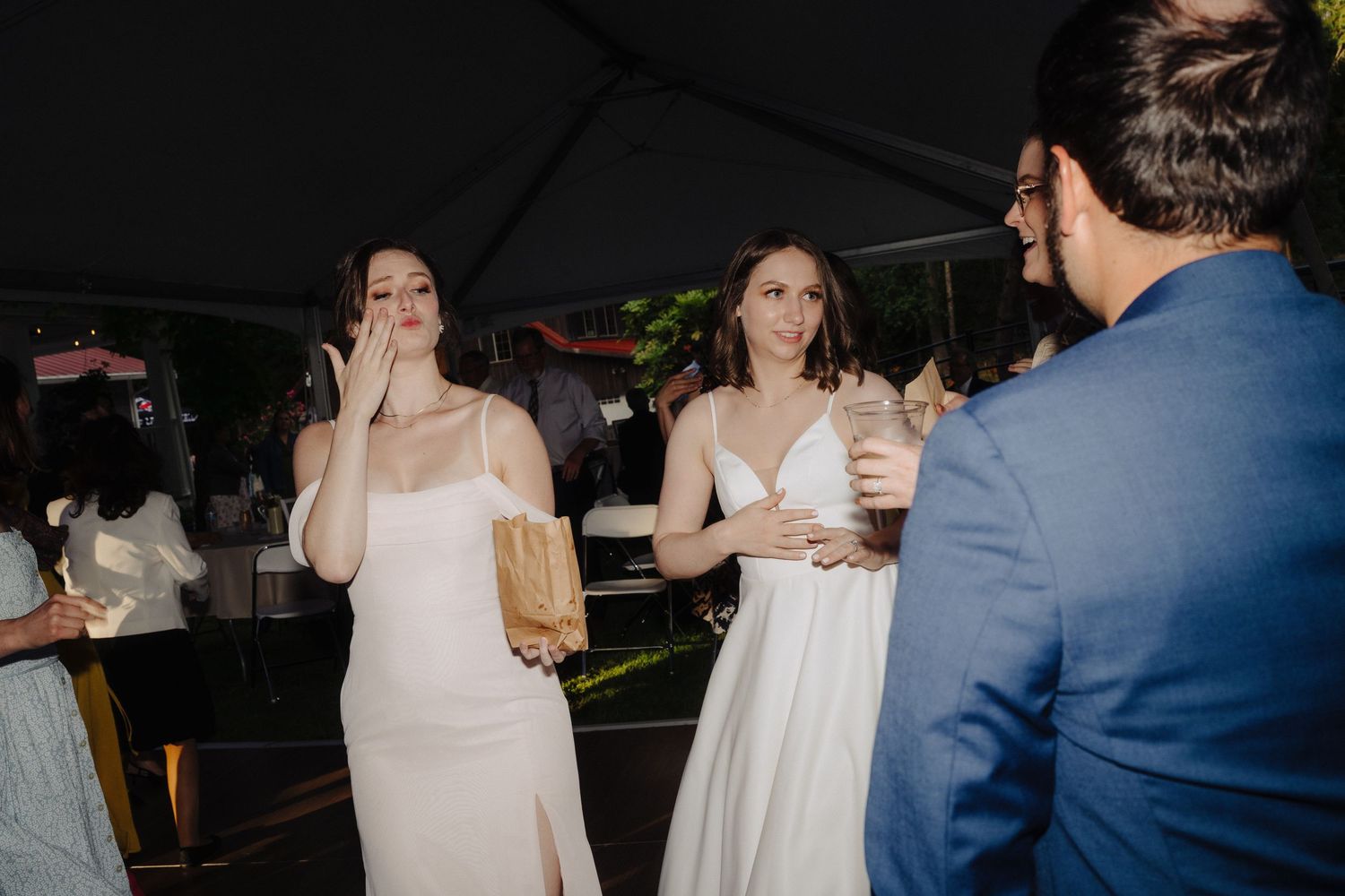 Wedding reception guests celebrate under evening lighting at an outdoor venue.