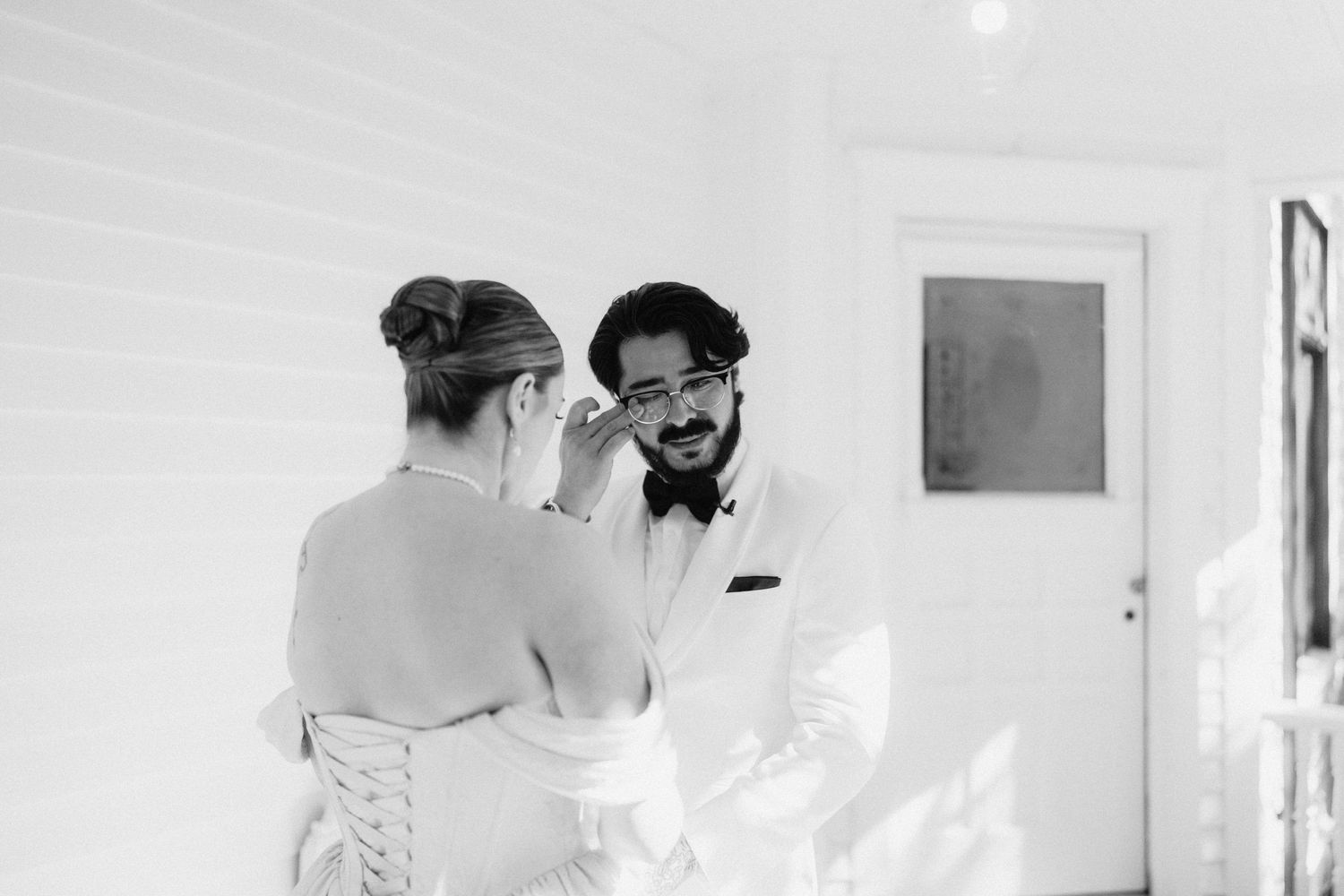 Two people share a joyful moment in a bright white room.