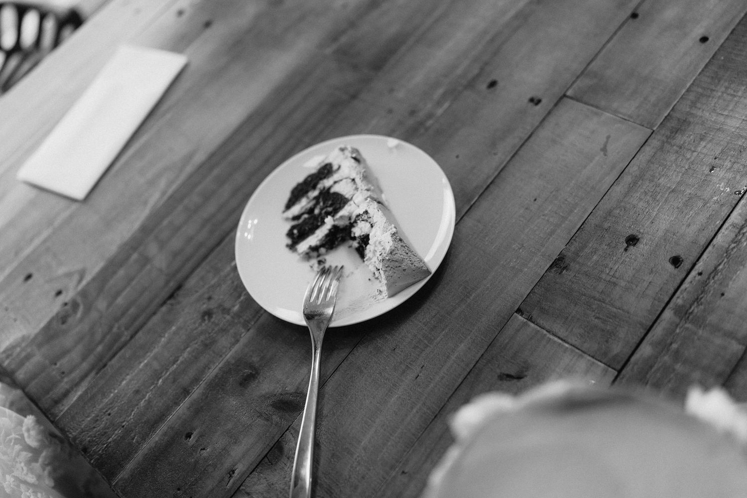 Black and white photo of empty plates and utensils on rustic wooden table.
