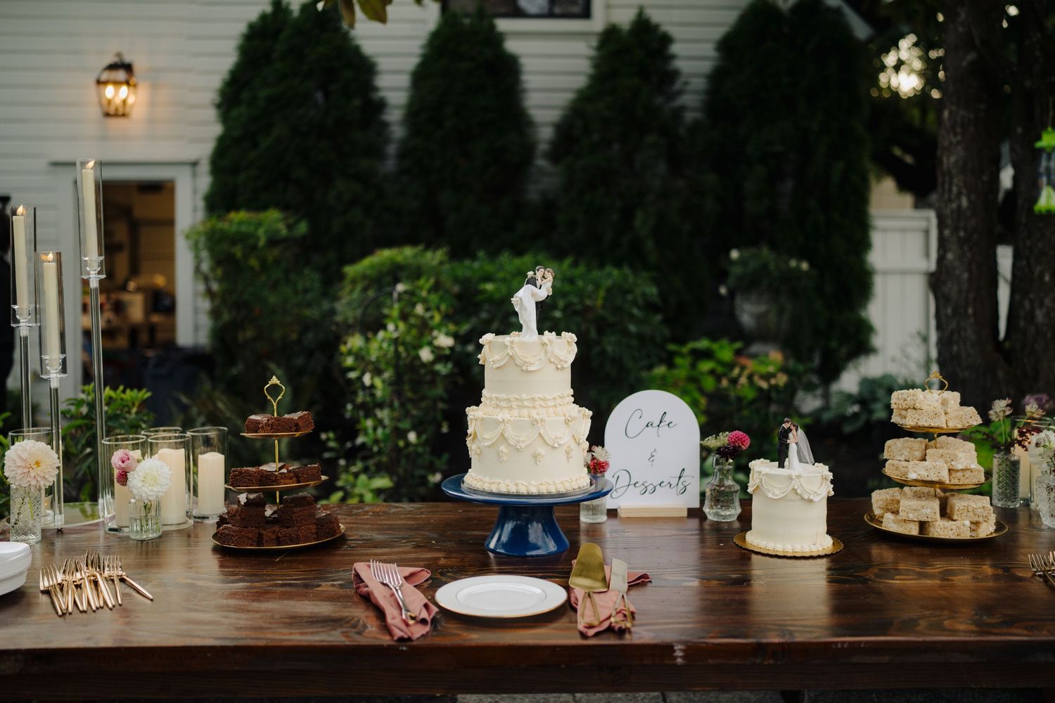 Rustic dessert table display featuring white wedding cakes and vintage decor elements.