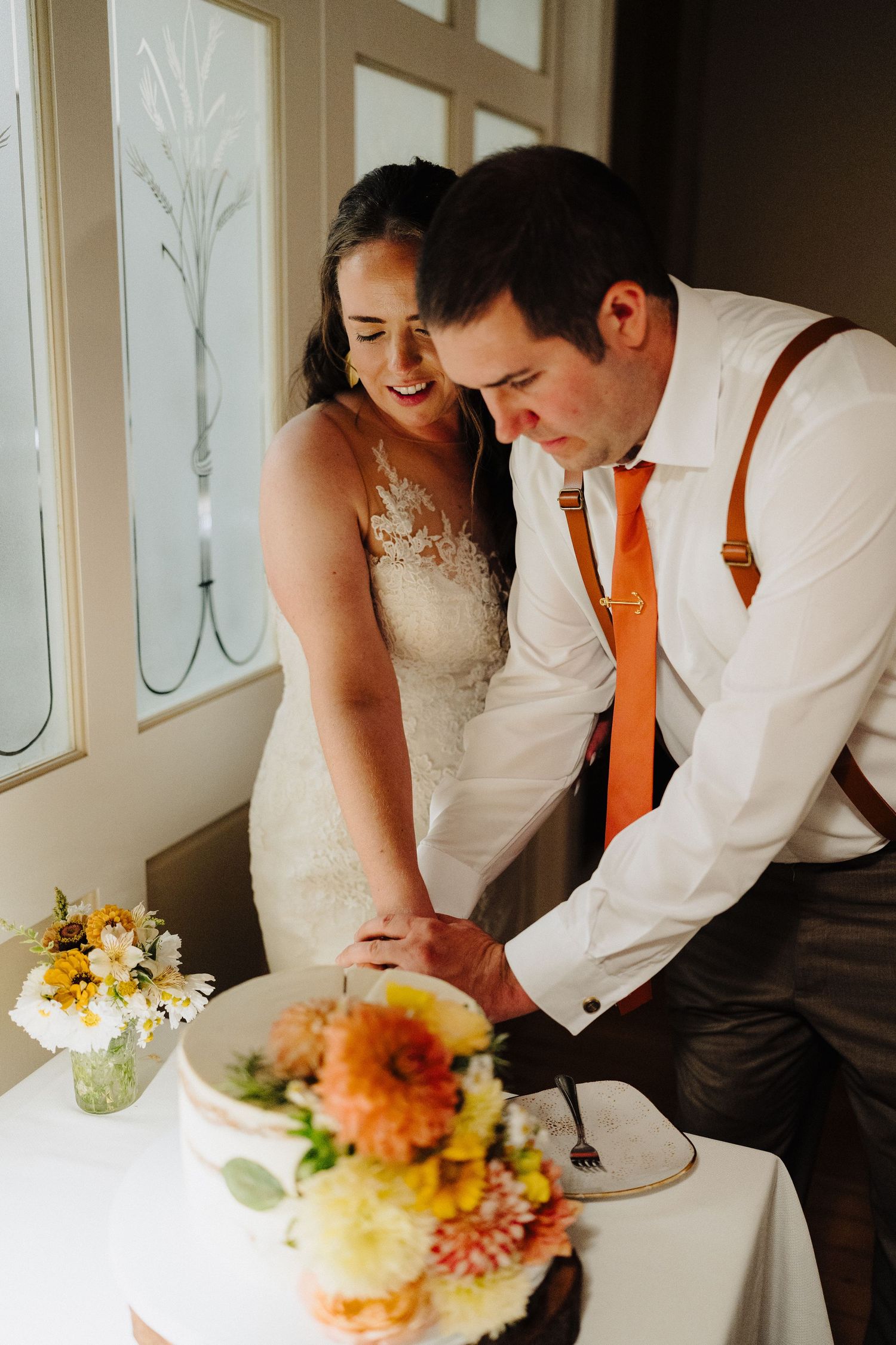 A couple cuts their wedding cake together during an intimate reception moment.