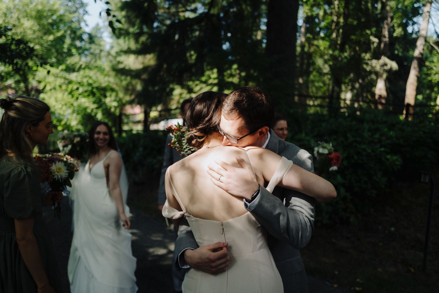 Candid moments captured during an outdoor wedding celebration in a wooded setting.