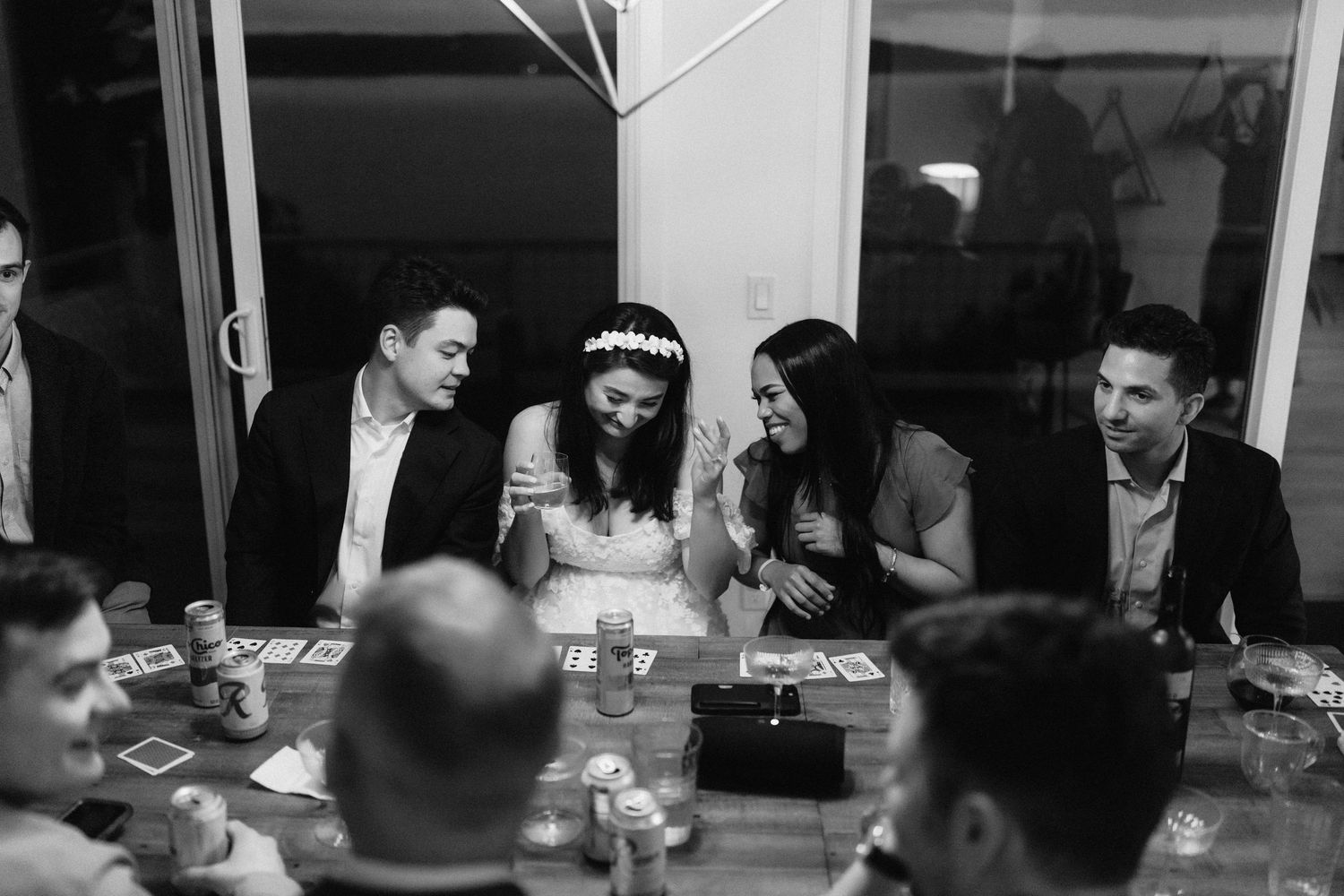 A black and white photo of wedding guests dining and socializing at reception tables.