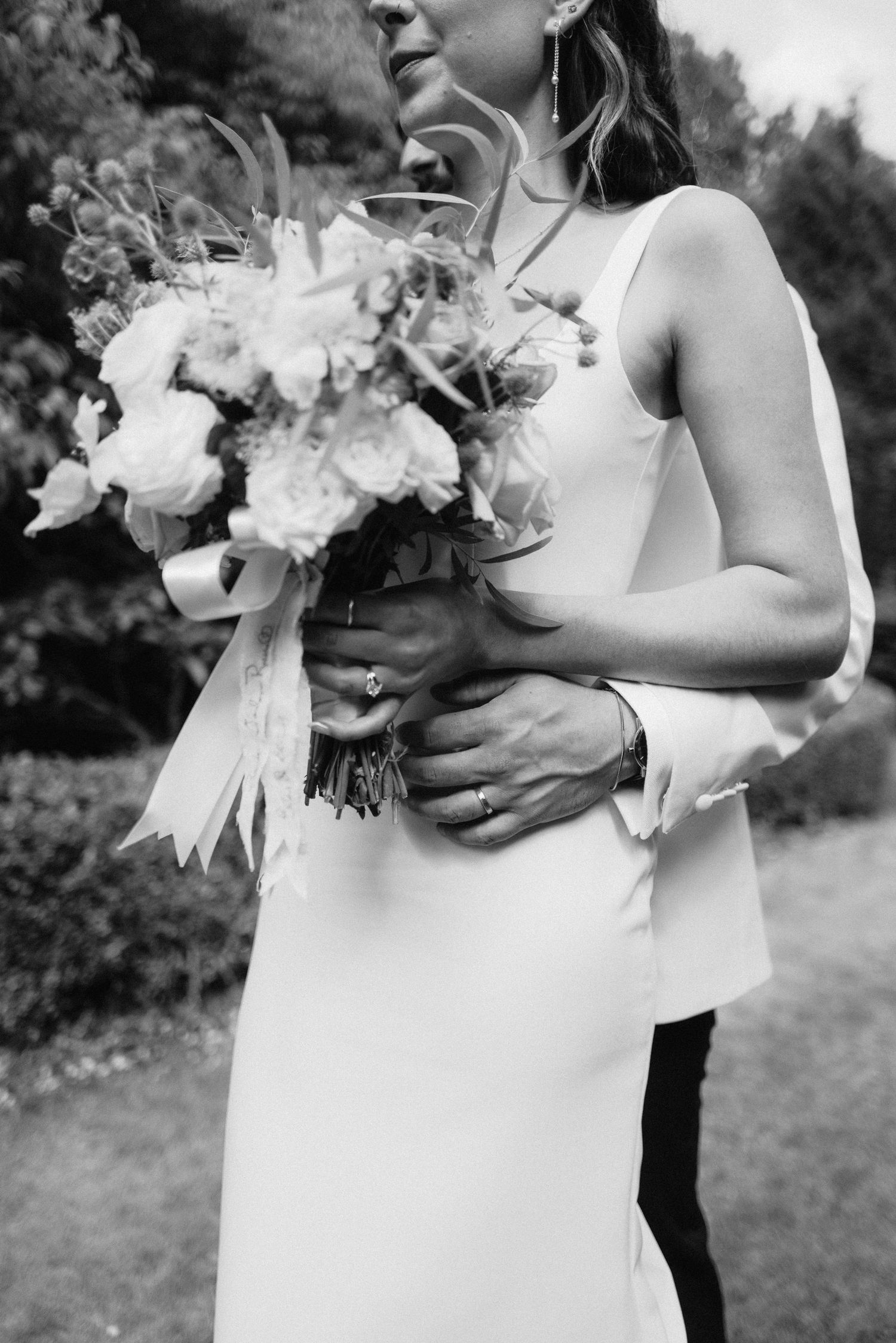 Close-up of white wedding bouquets with elegant ribbons against formal attire.