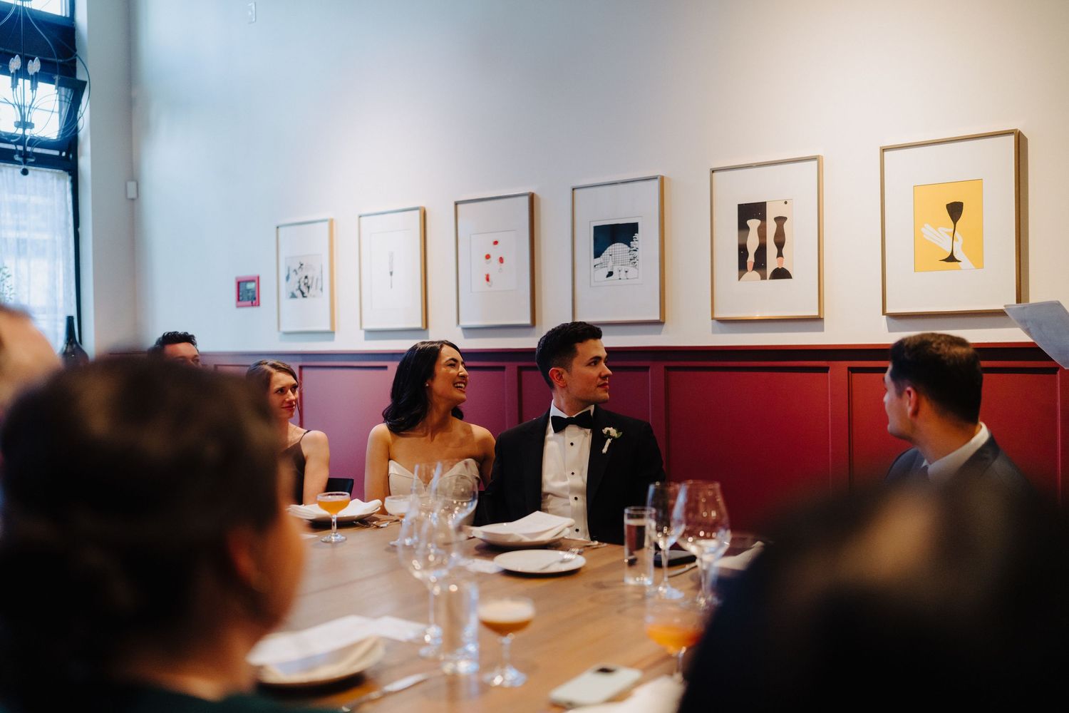 Wedding reception in modern art gallery with framed artwork on walls.
