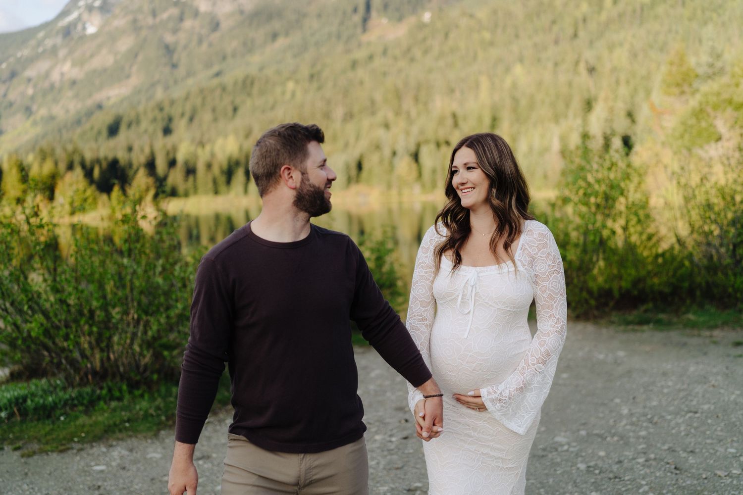 Romantic outdoor portrait session by mountain lake with dramatic mountain peaks in background.