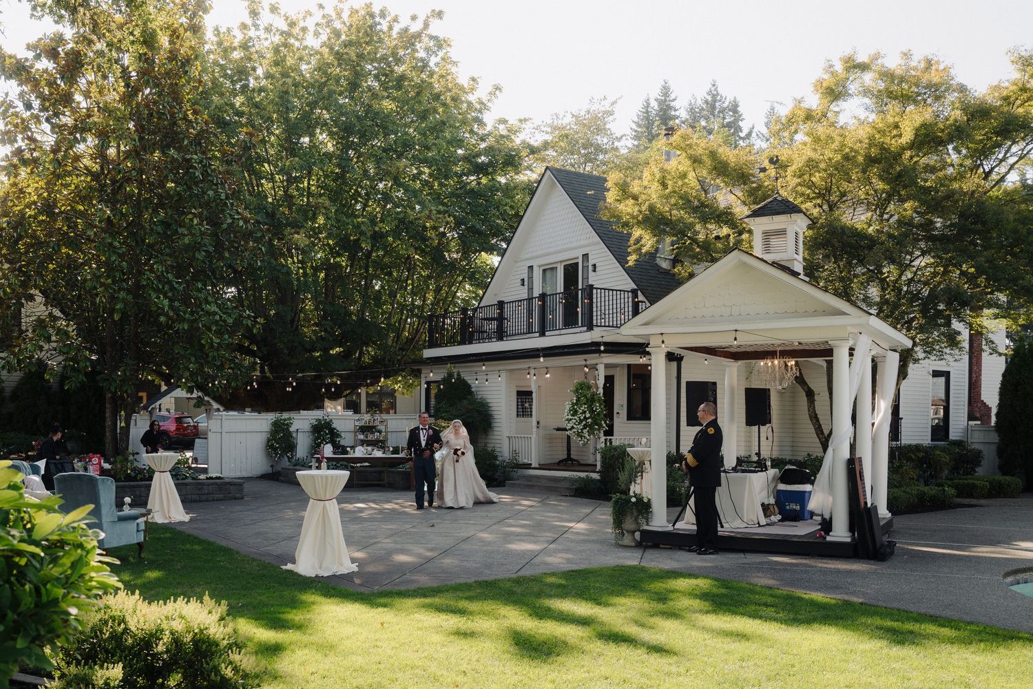 Panoramic view of a historic white wedding venue surrounded by lush trees and gardens.