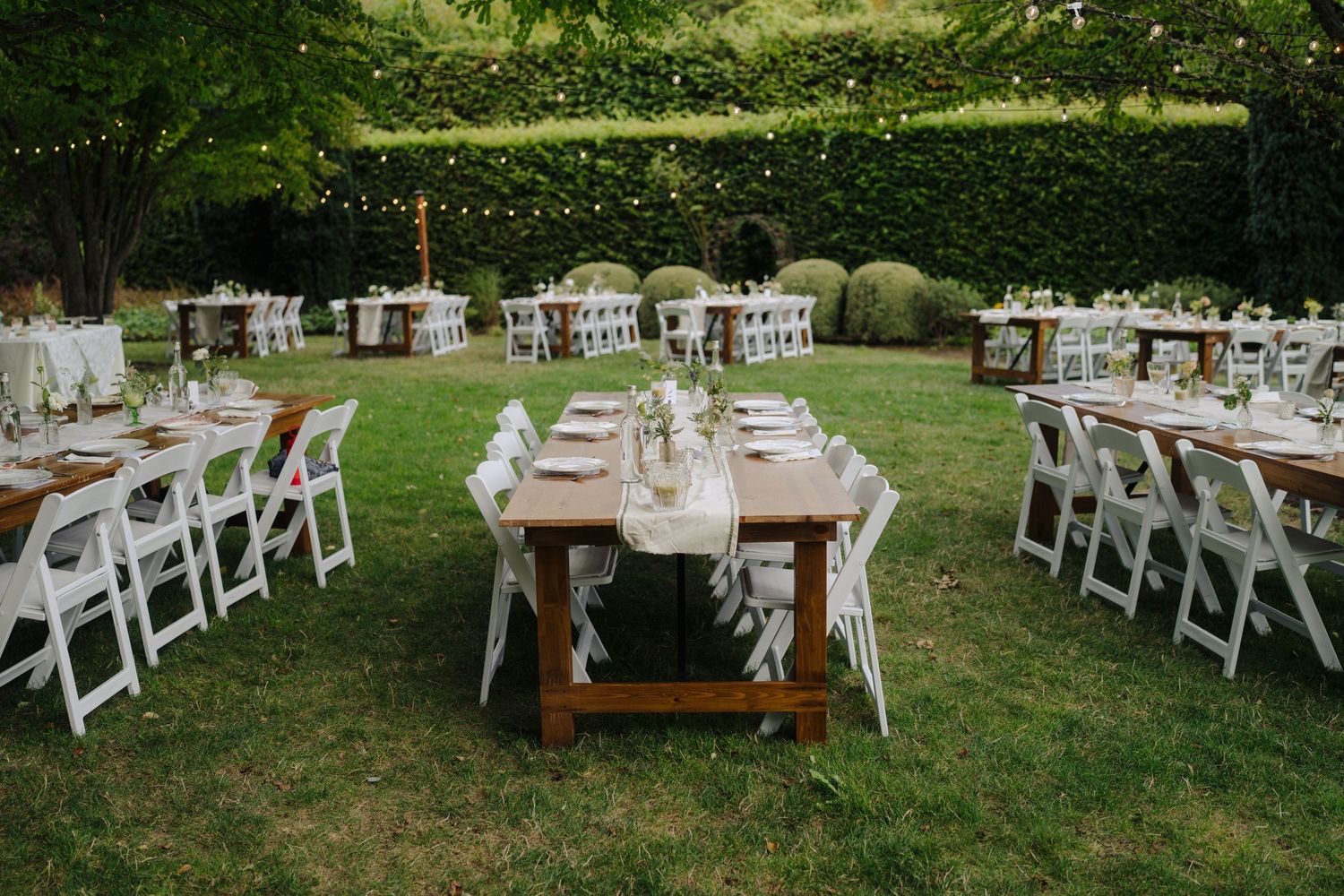 White folding chairs arranged in rows on a lawn for an outdoor wedding ceremony.