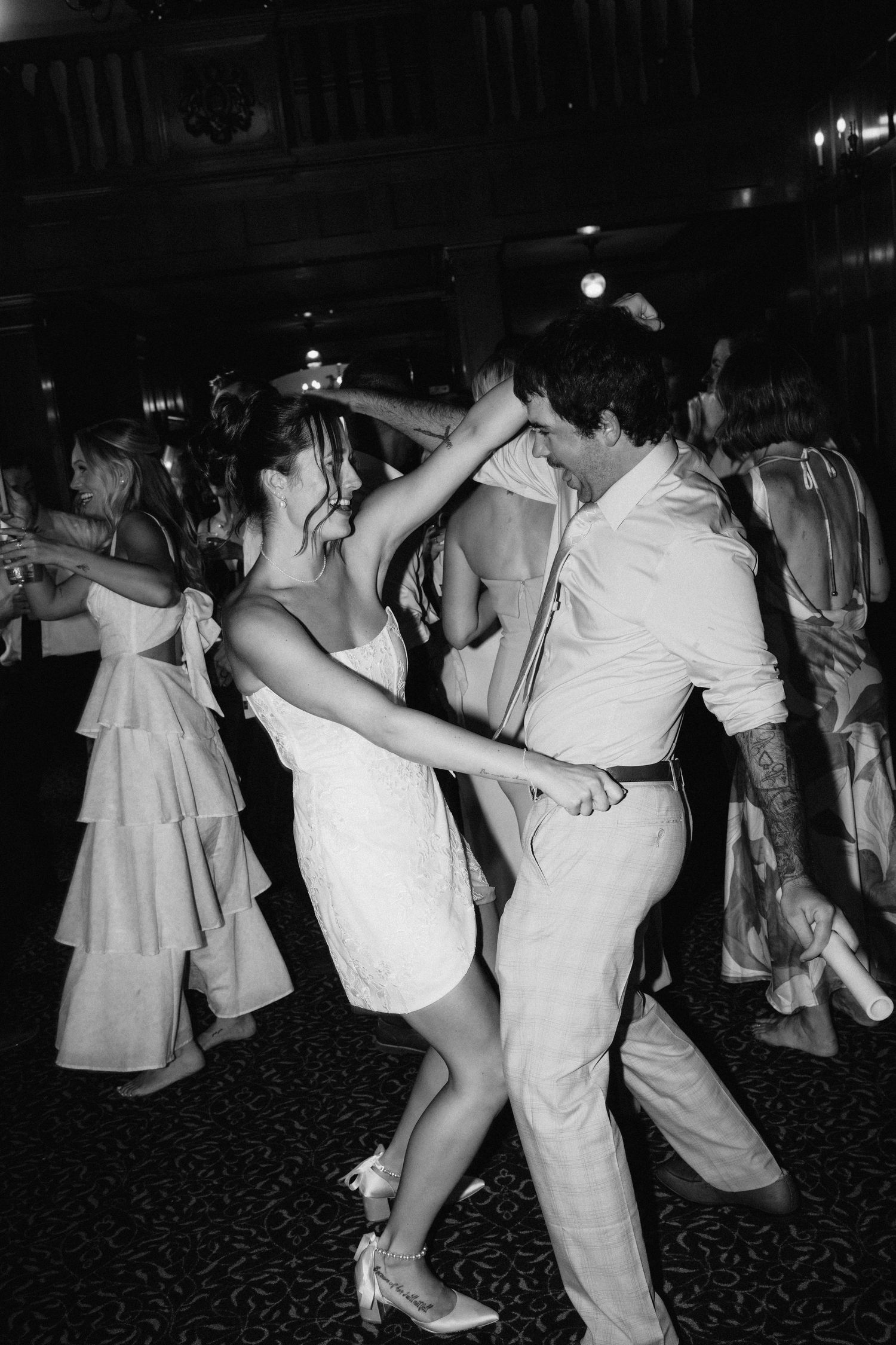 Wedding reception guests dancing energetically on a patterned carpet dance floor.