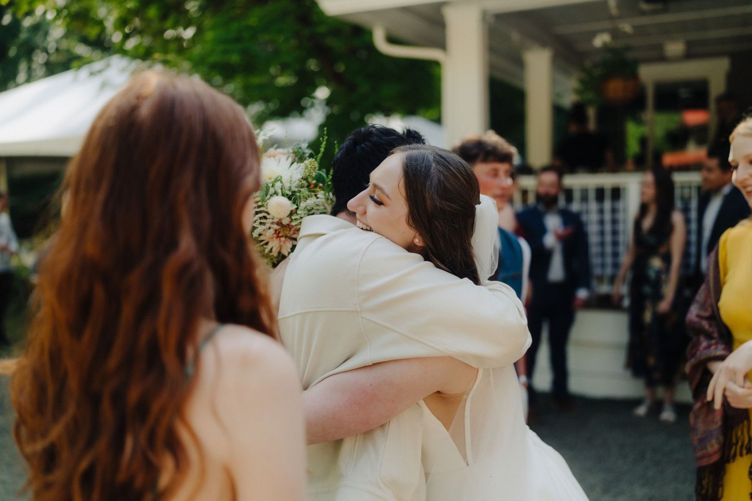 Wedding guests sharing embraces during an outdoor celebration.