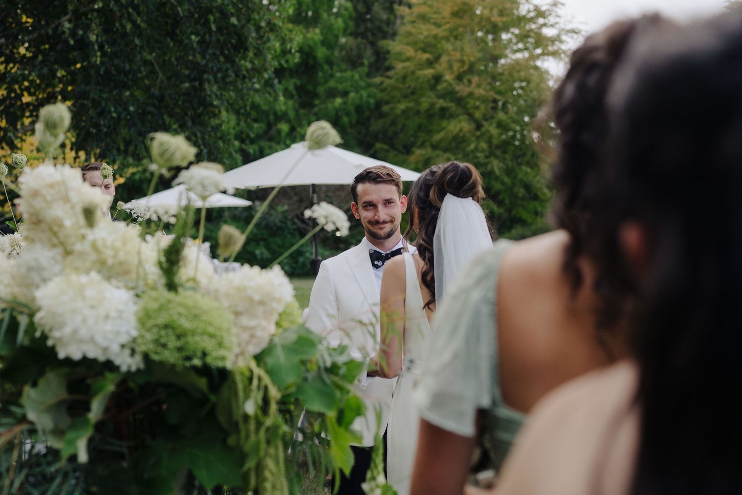 Guests mingle at an elegant outdoor wedding reception with lush floral arrangements.
