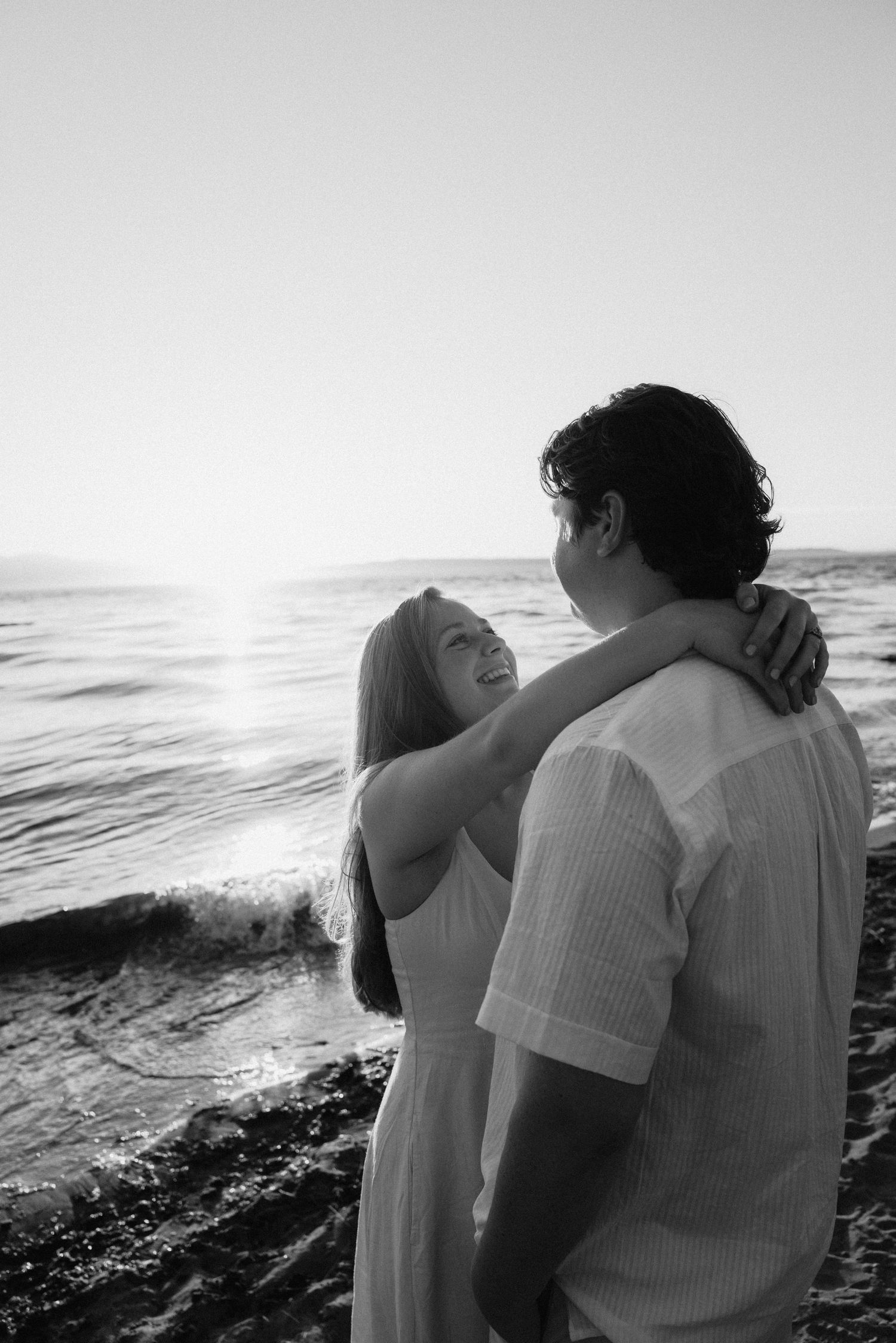 A silhouetted couple shares an intimate moment against a dramatic ocean backdrop at sunset.