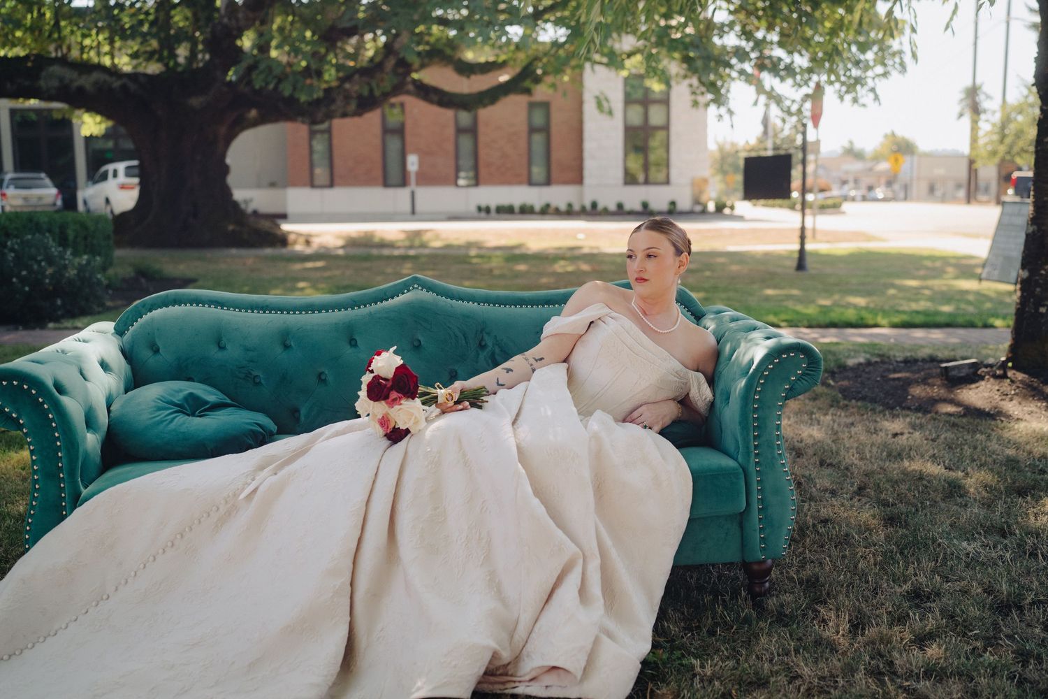 Wedding couple relaxing on a teal vintage sofa outdoors during their photoshoot.