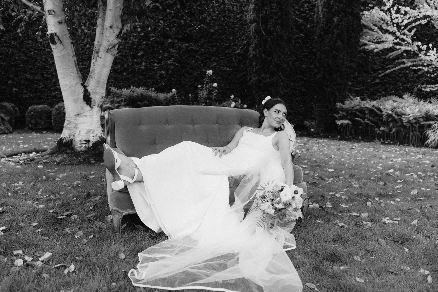 Black and white wedding photo showing couple embracing on garden grounds.