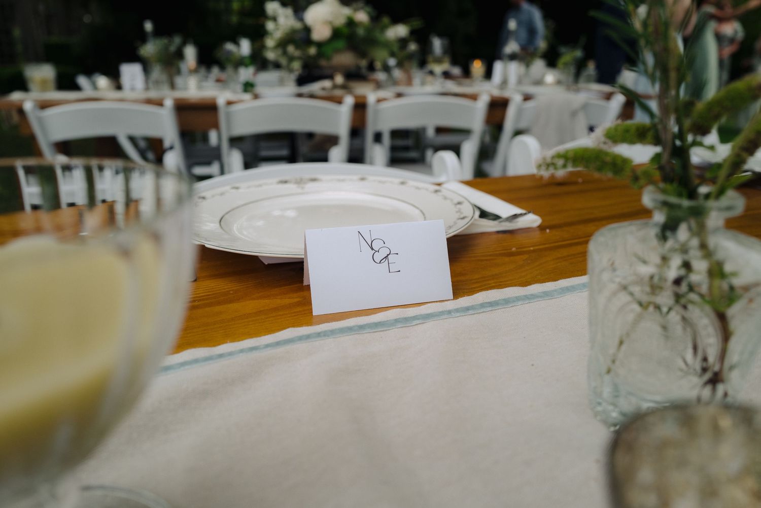 A white place card and wine glass on a wooden table at an elegant wedding reception.