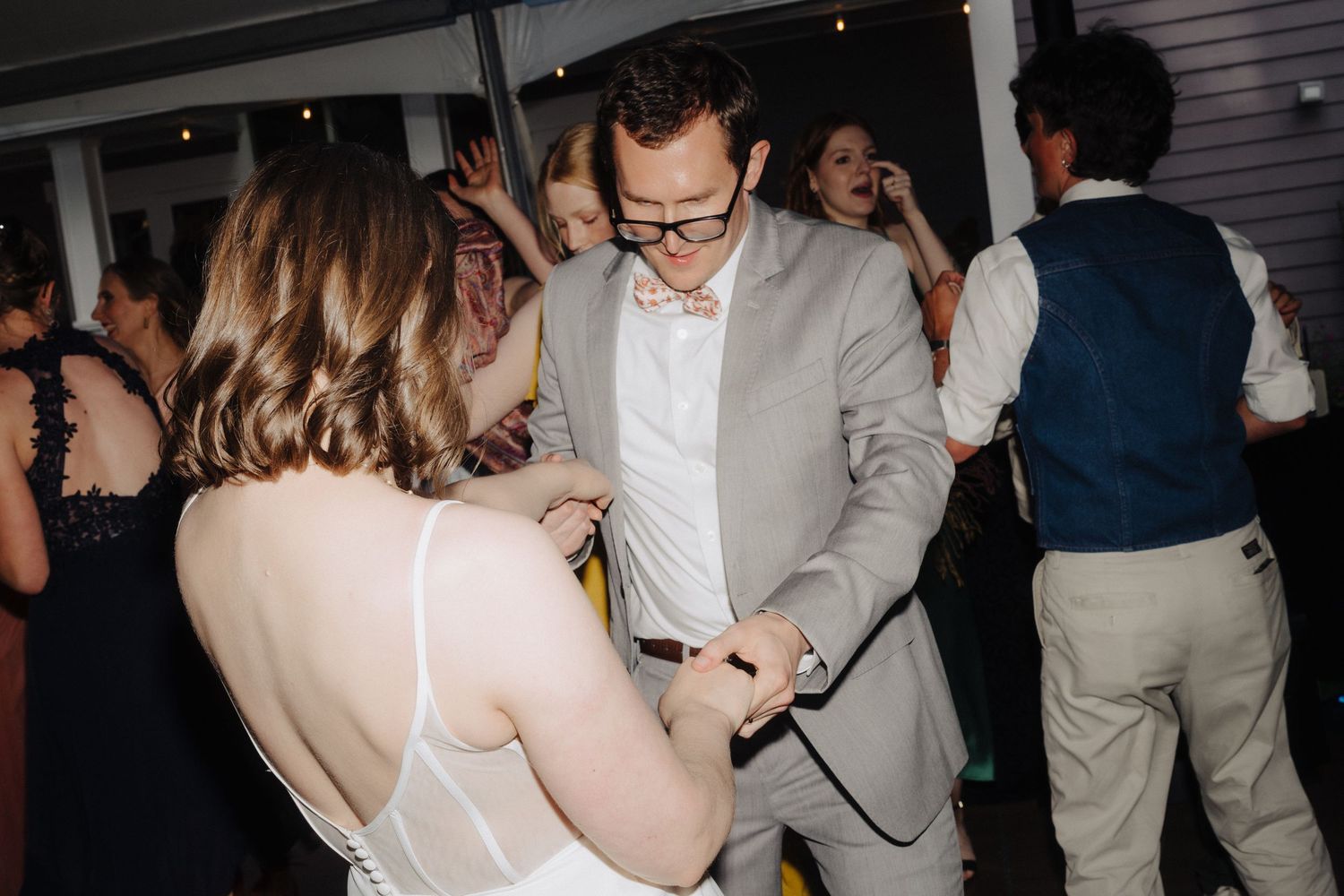 Wedding reception dance party photos with guests celebrating under dim lighting.