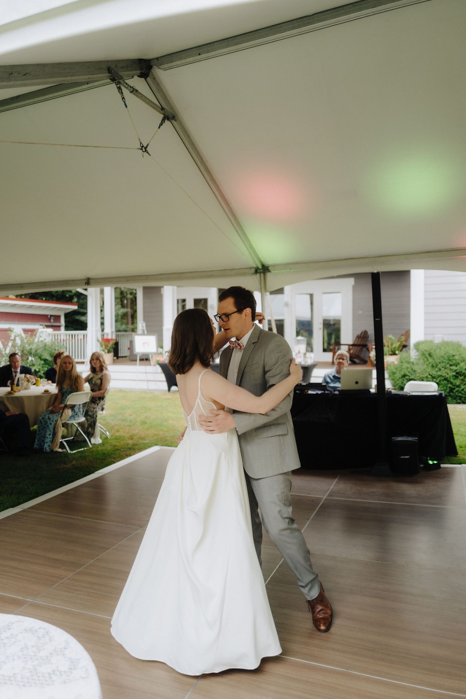 First dance under a white tent reception with wooden flooring.