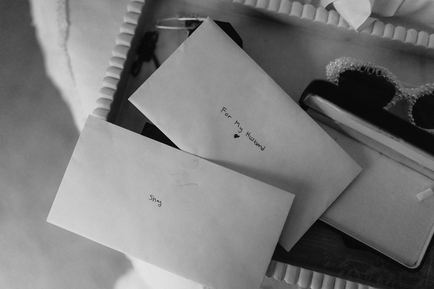 Black and white photo of paper documents arranged on a wooden table surface.