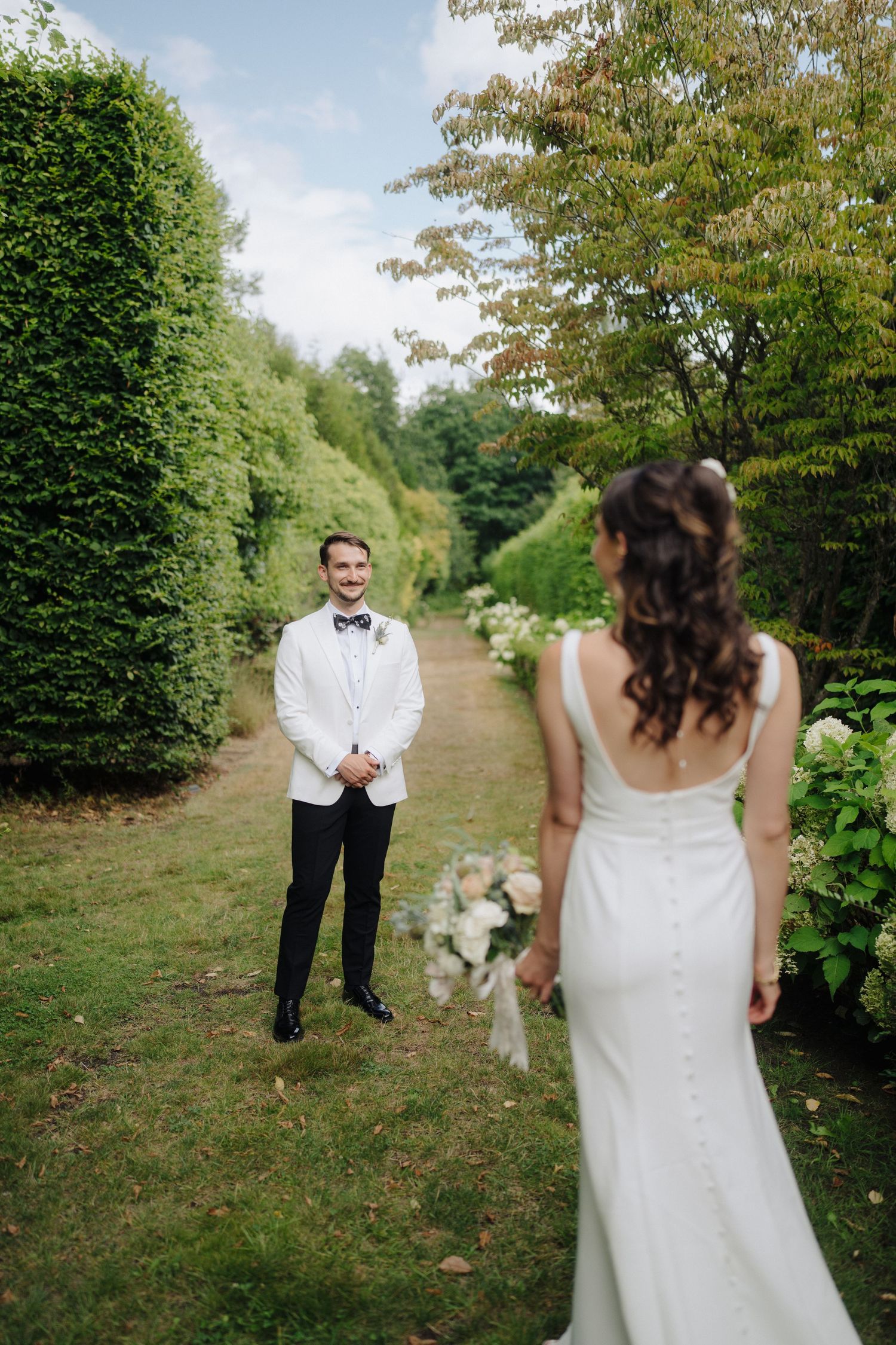 A romantic first look moment between newlyweds in an outdoor garden setting.