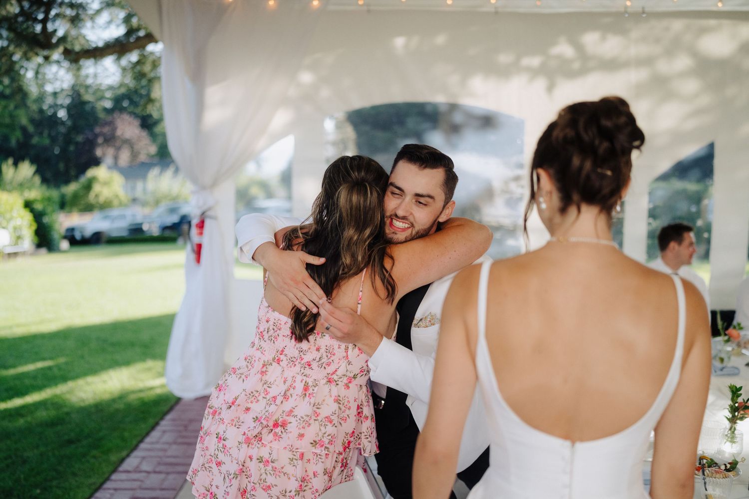 Joyful celebration moment under a white tent at an outdoor wedding reception.