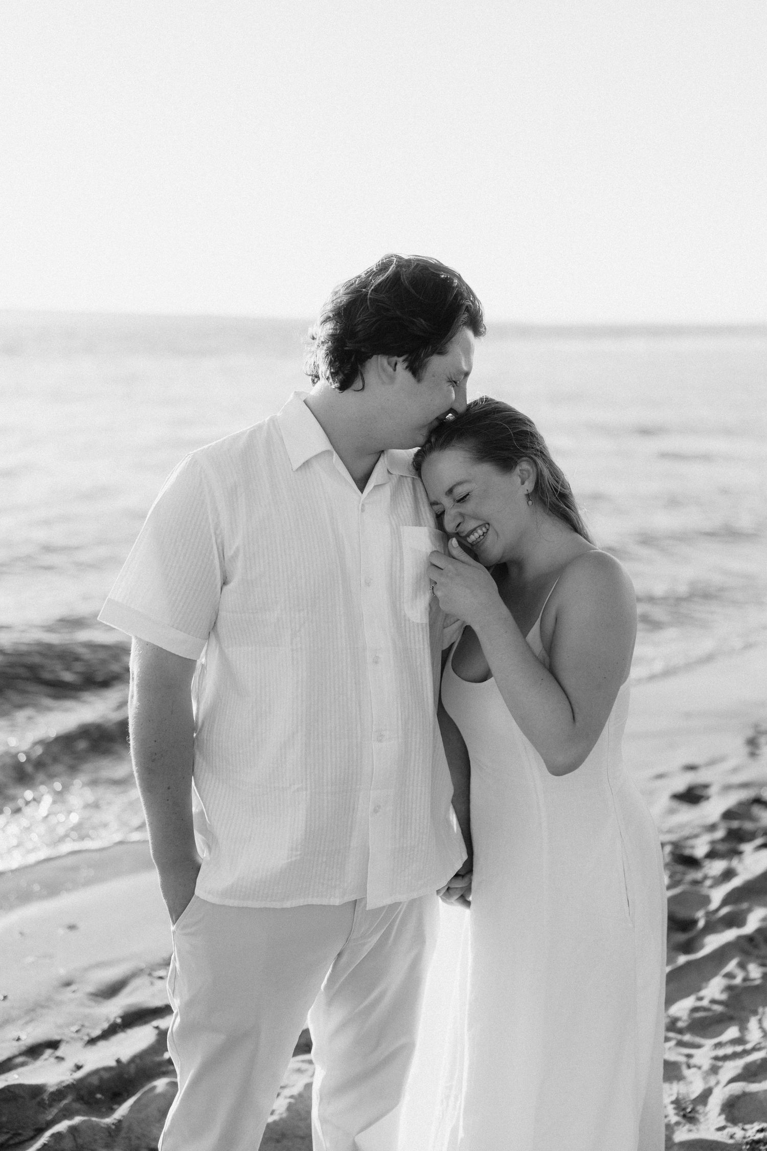 A romantic black and white photo of a couple sharing a joyful moment together on the beach.