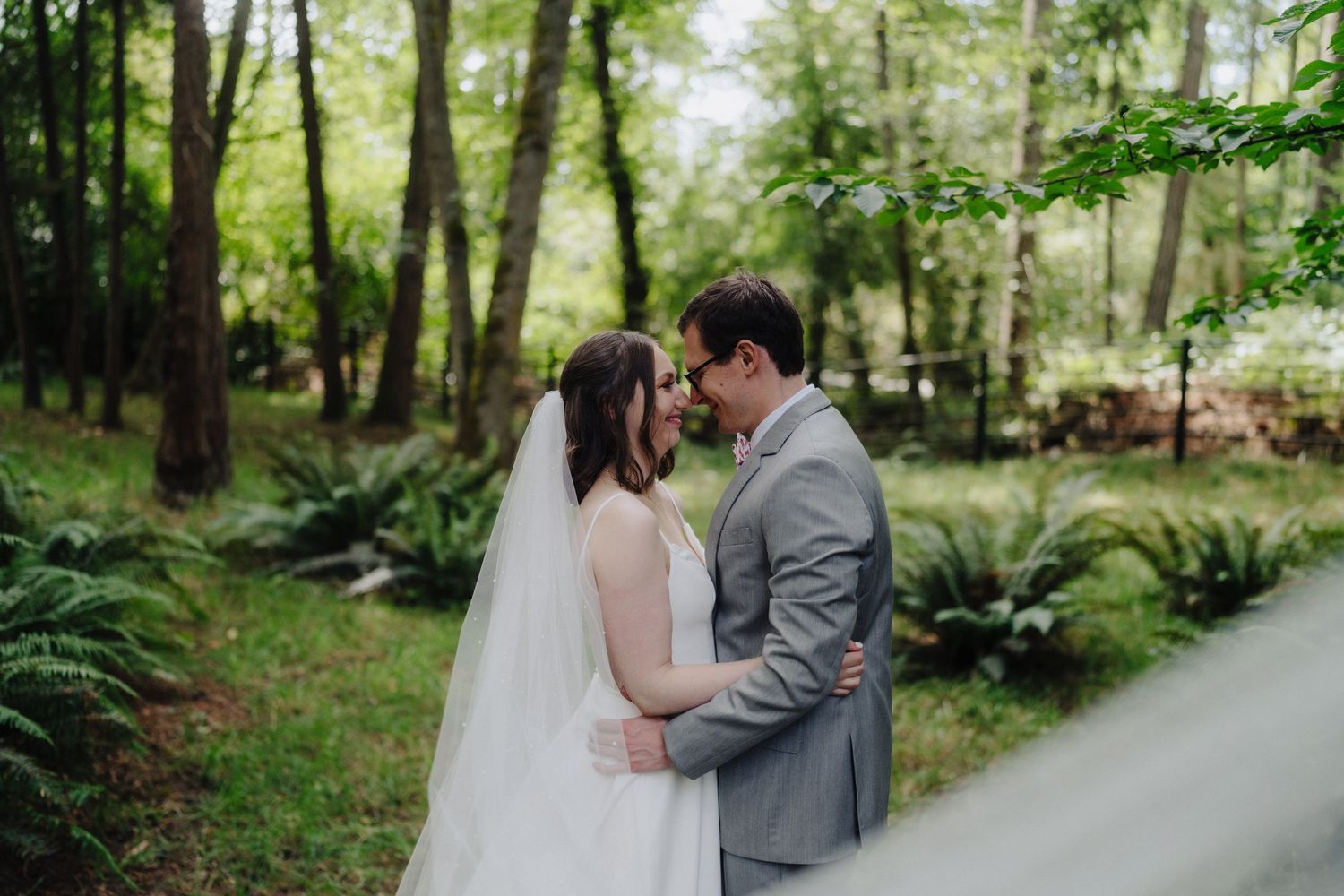 Couple shares tender moments along a forest path surrounded by lush greenery.