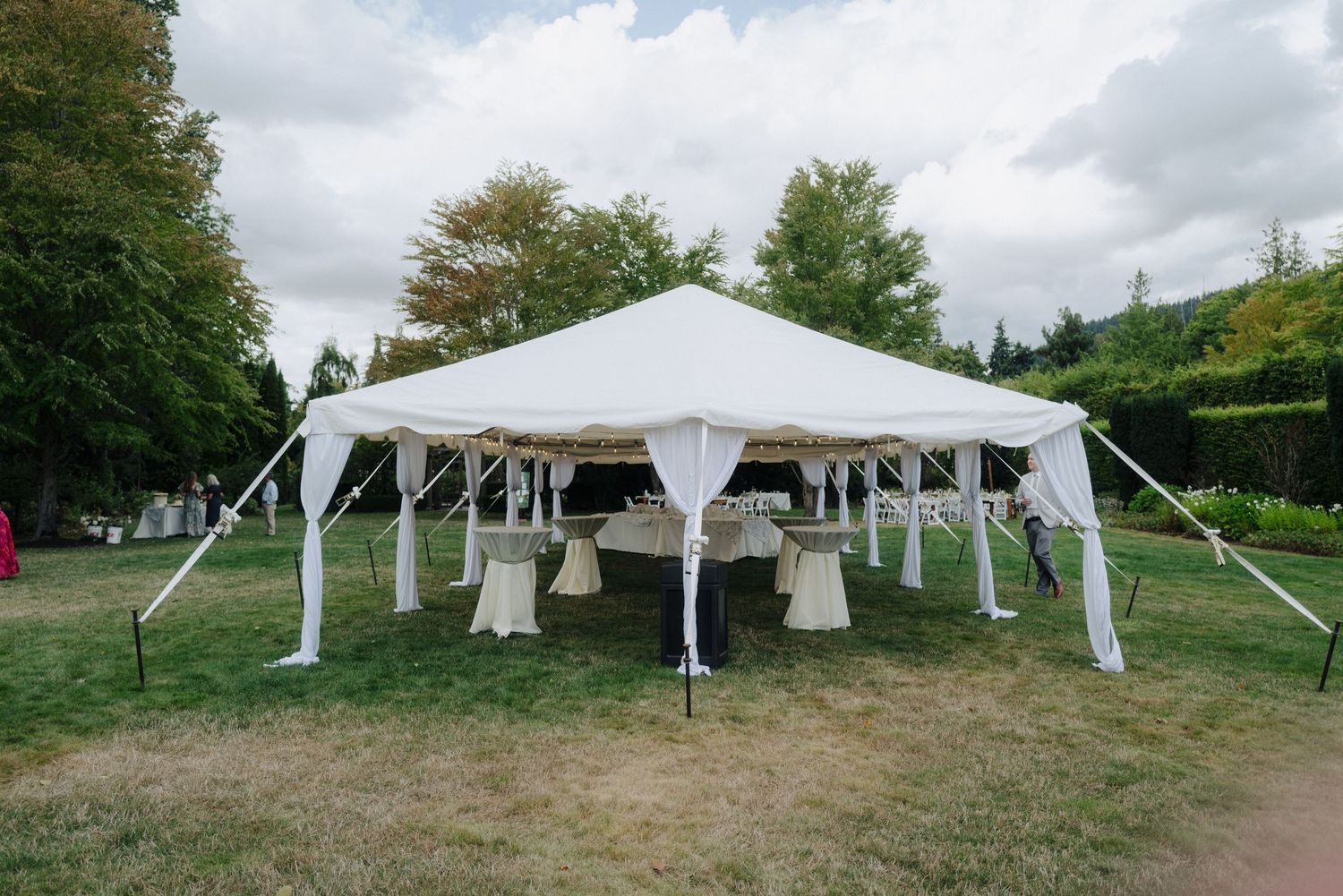 Row of white wedding tents set up on a hillside for an outdoor celebration.