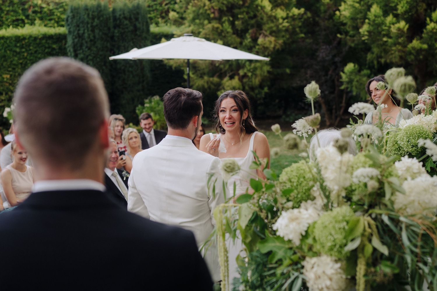 An outdoor wedding ceremony setup with white floral arrangements and natural greenery.
