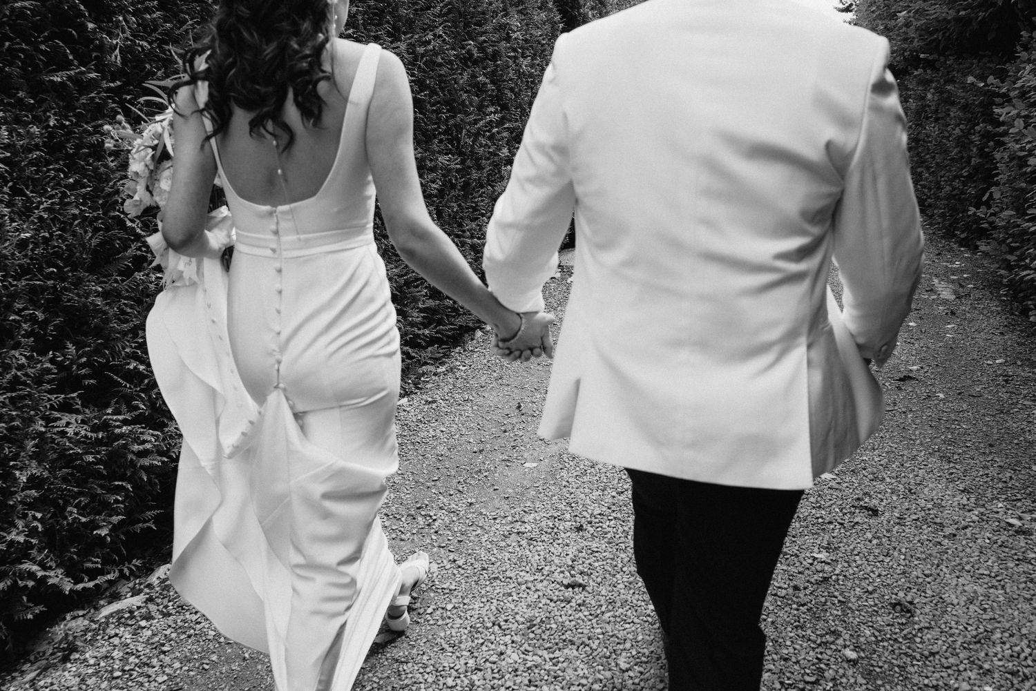 Wedding couple walking together on a garden path in formal attire.