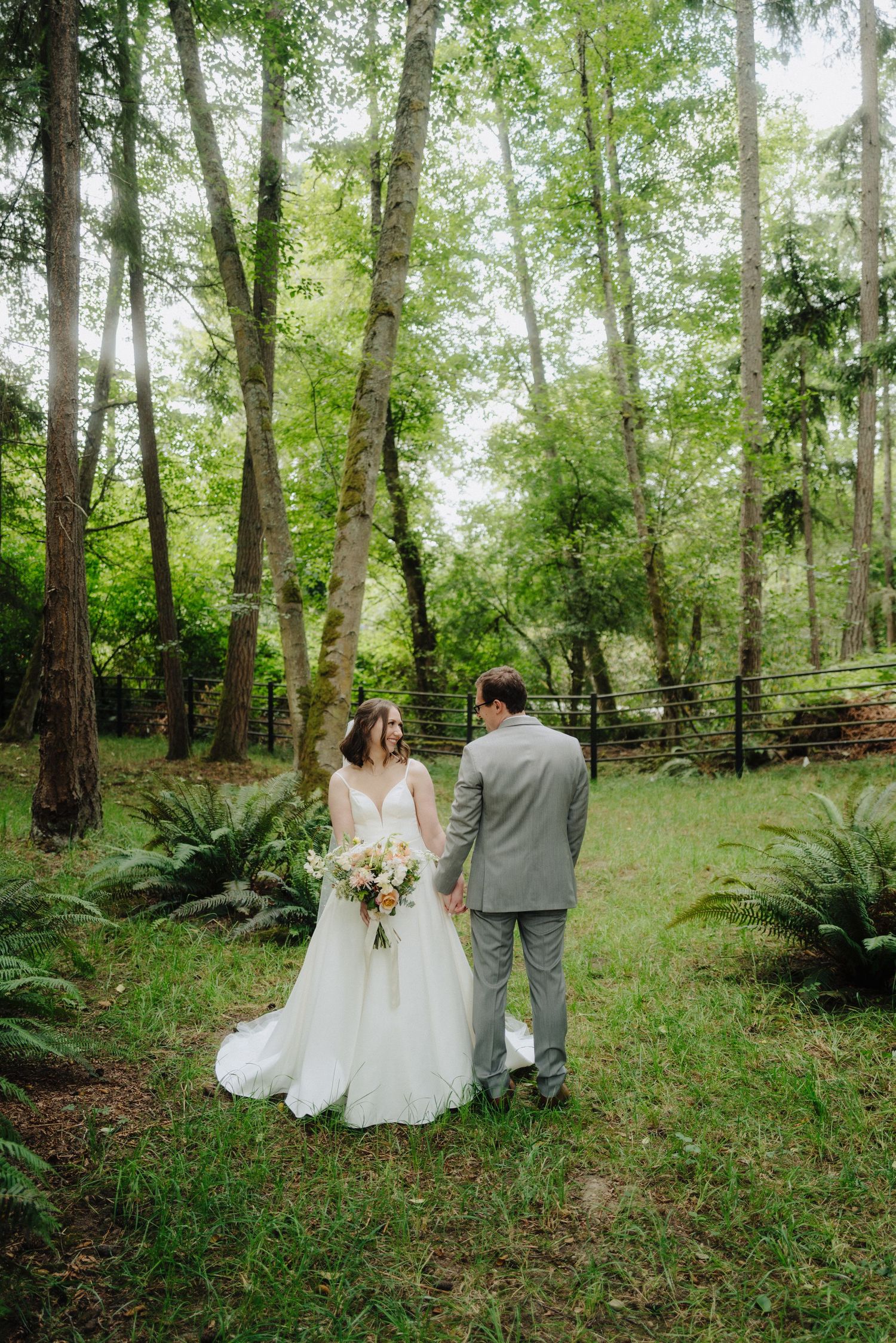 Couple walking through a serene wooded area during their wedding photoshoot.
