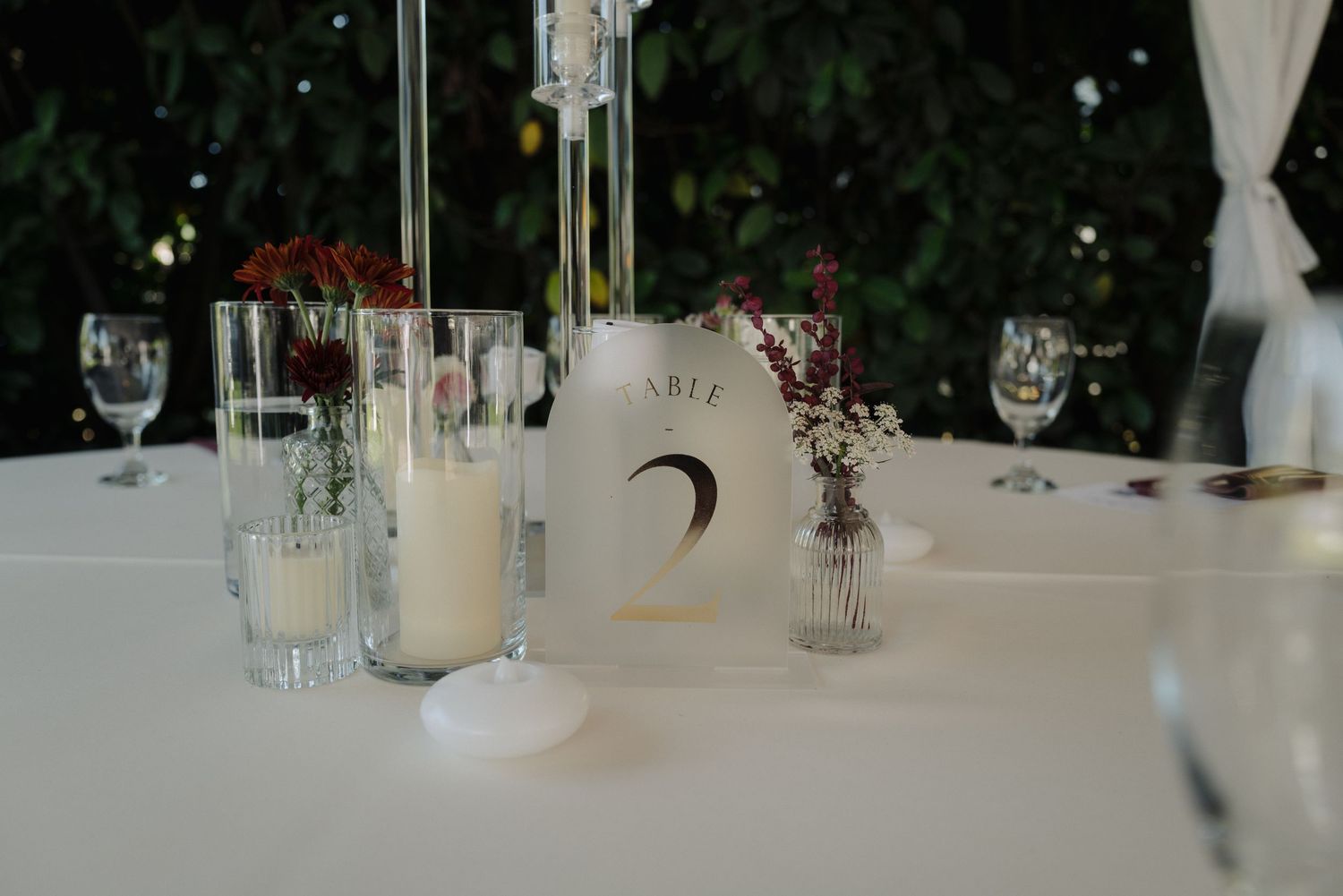 Elegant white wedding reception setup with glassware and floral centerpieces.