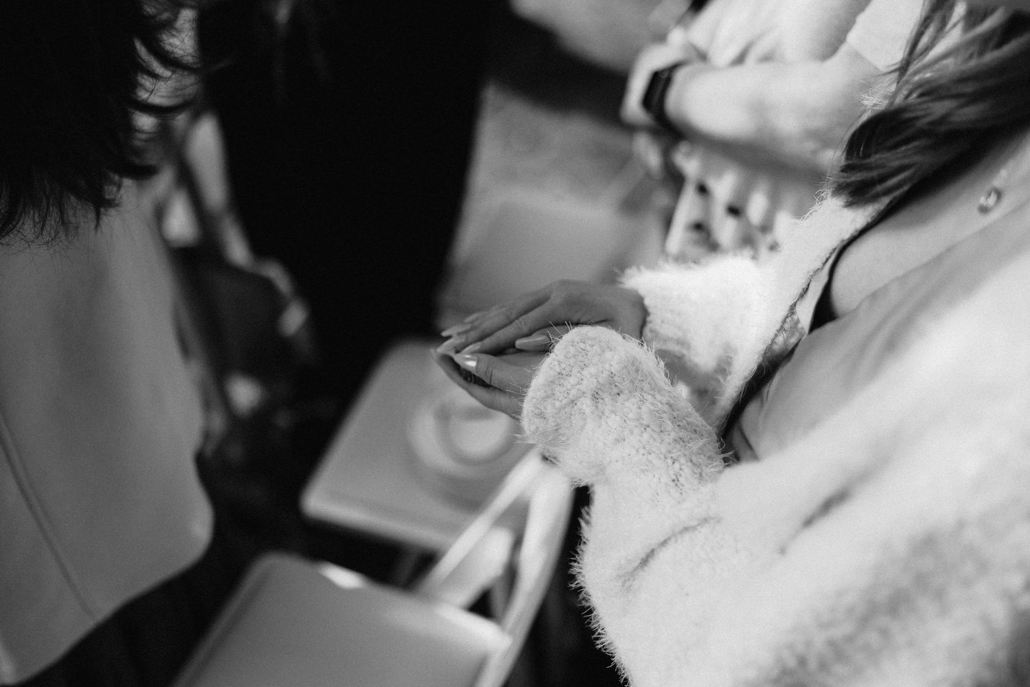 Close-up black and white photograph of hands holding a makeup brush during wedding preparation.