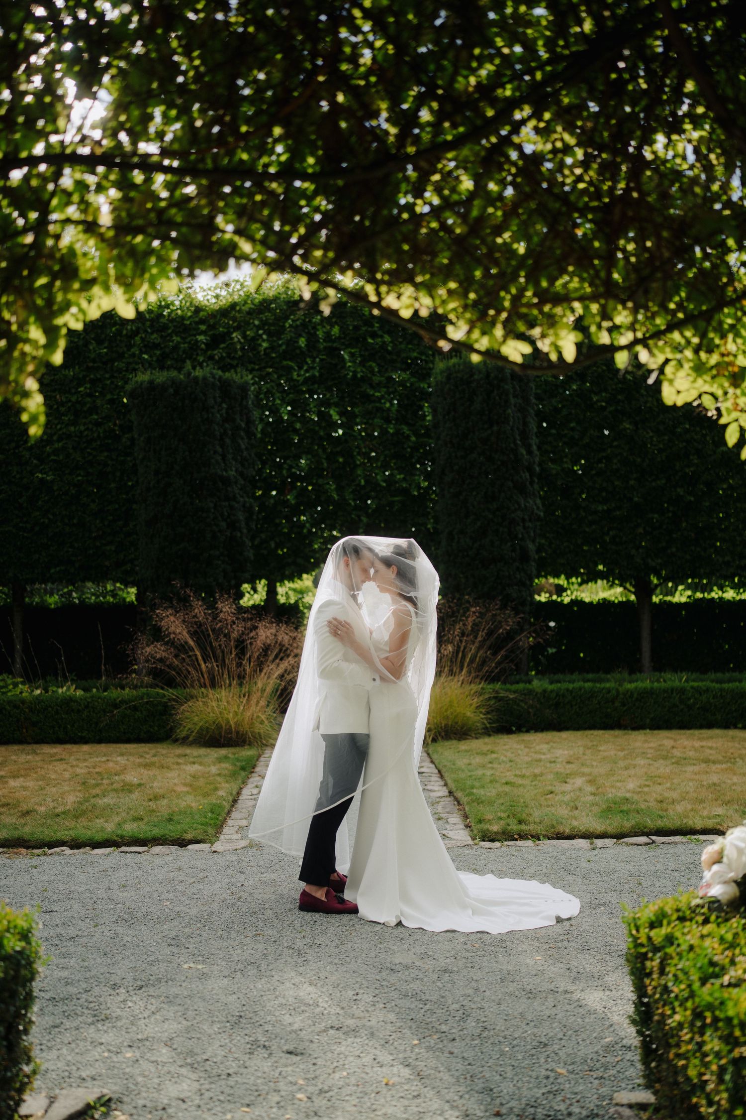 Wedding couple photographed under natural garden canopy with beautiful lighting.
