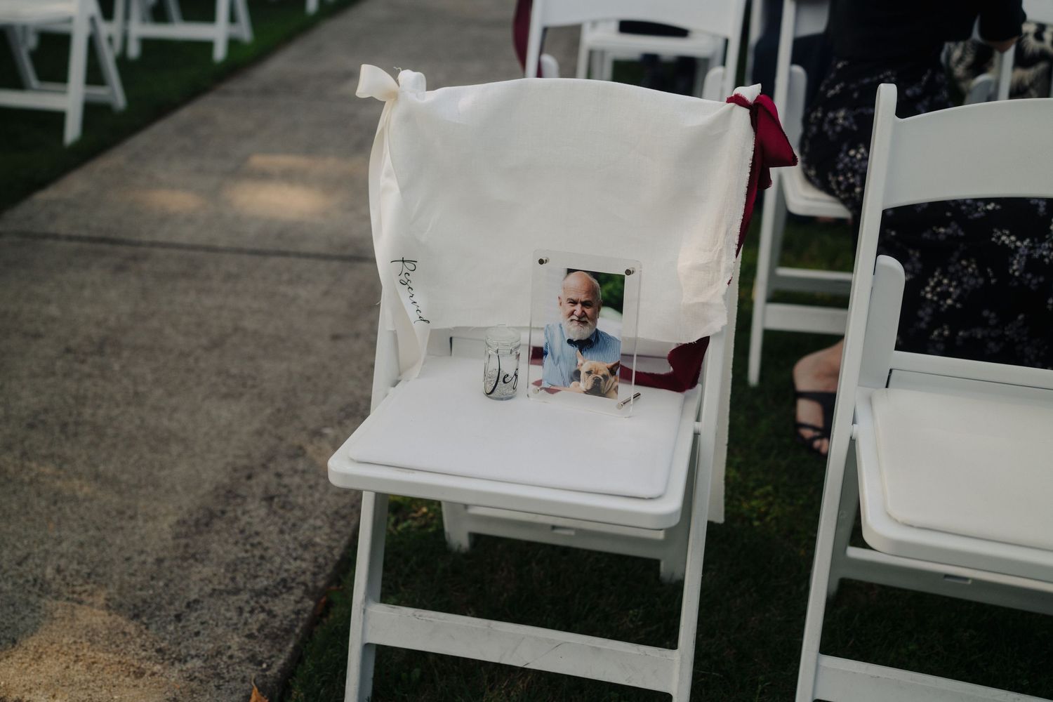 White folding chairs arranged in rows for an outdoor wedding ceremony.