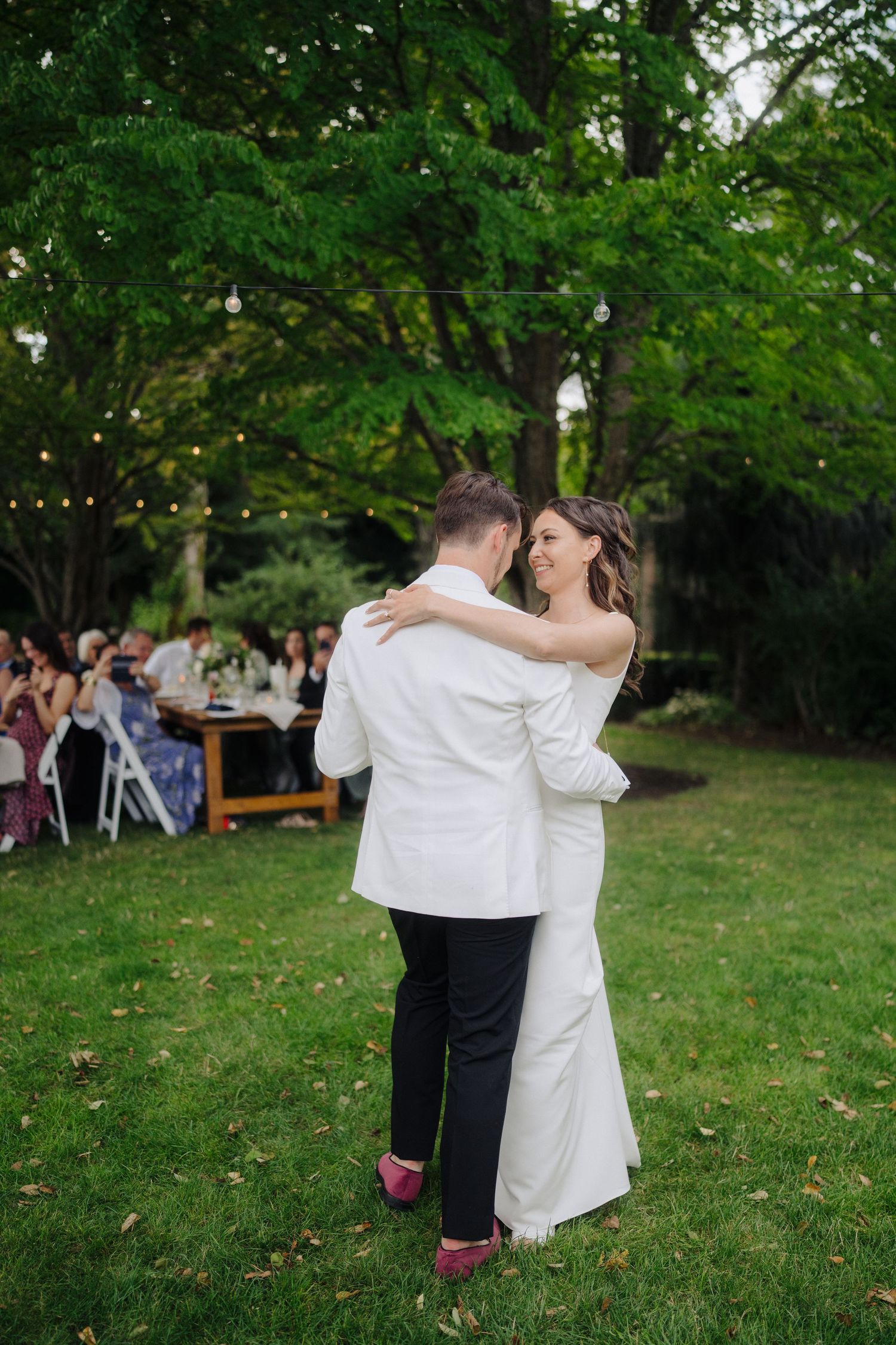 Couple sharing their first dance on the grass at an outdoor garden wedding reception.