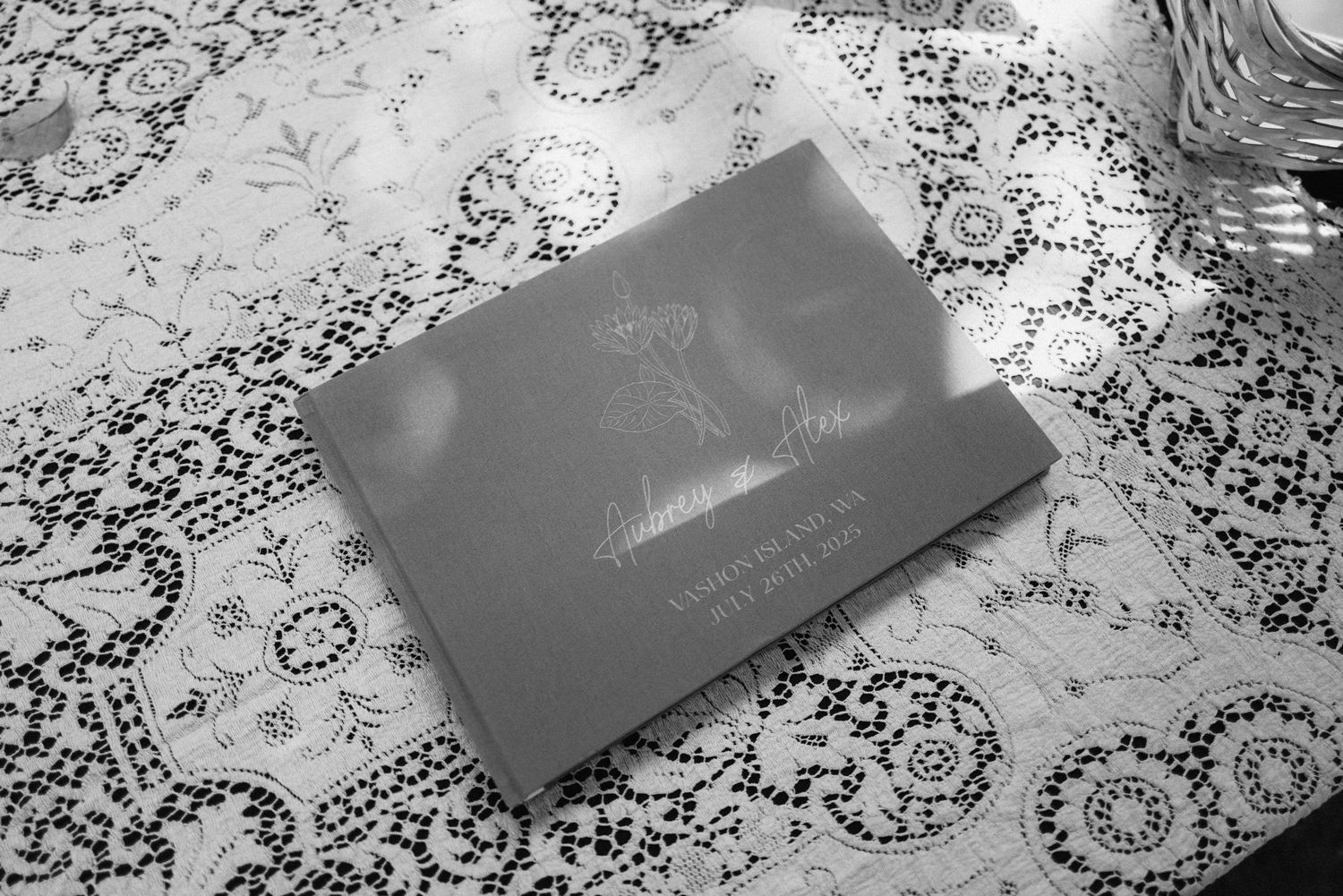 Wedding invitations or cards displayed on a white lace tablecloth in black and white photography.