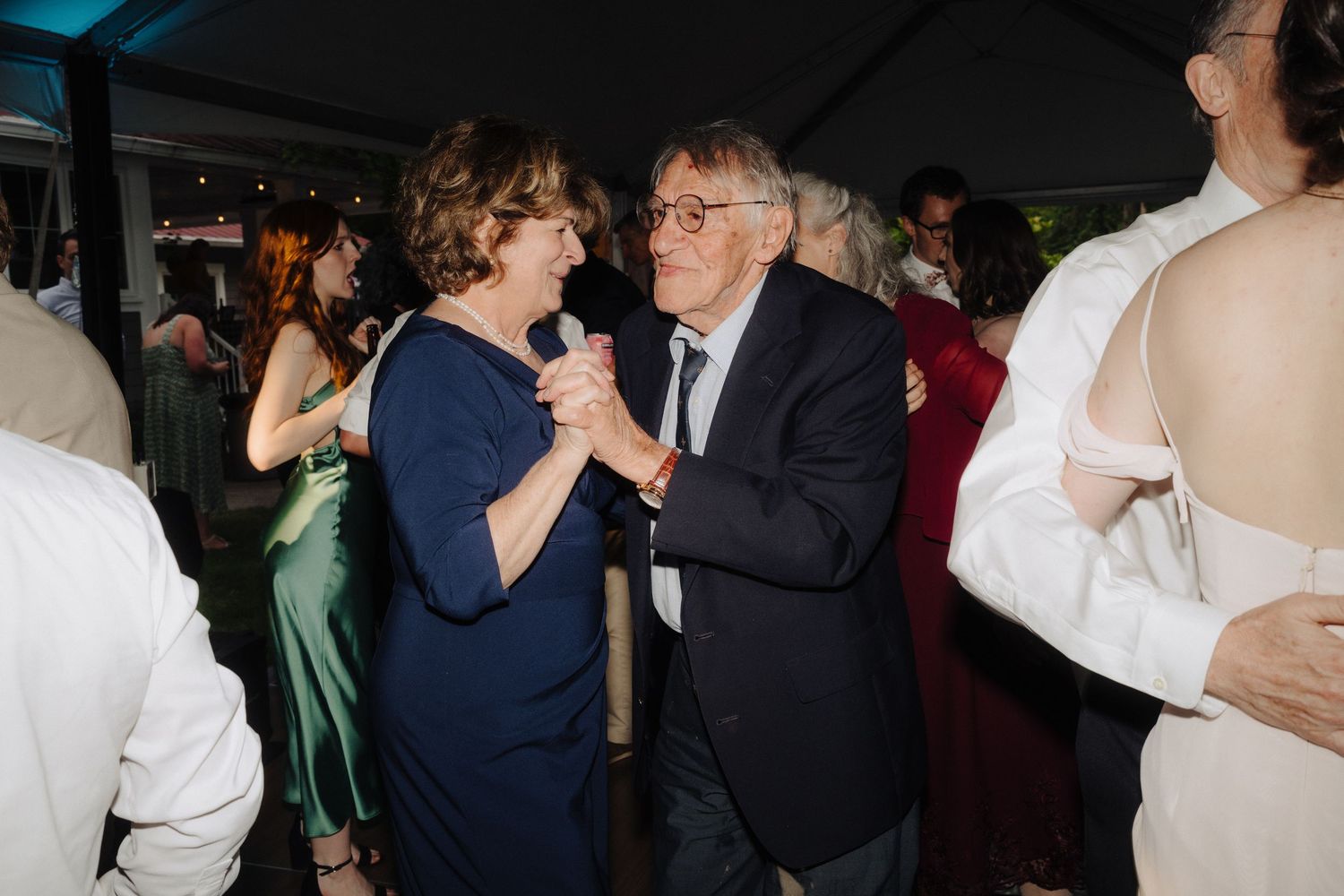 Wedding guests dancing and mingling at an indoor reception venue.