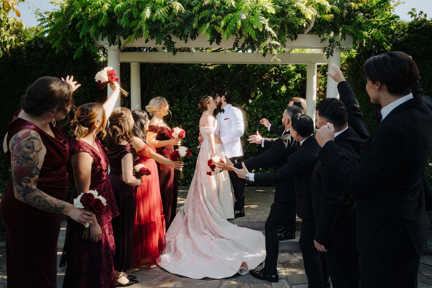 Wedding party celebrates outdoors with guests in formal attire.
