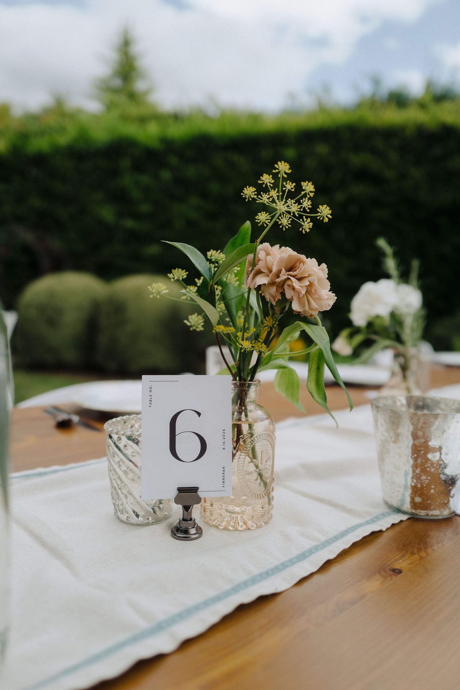 Elegant table settings with small floral centerpieces and table numbers for a wedding reception.