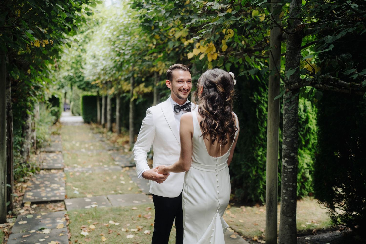 A joyful wedding moment captured between two people in white attire surrounded by trees.