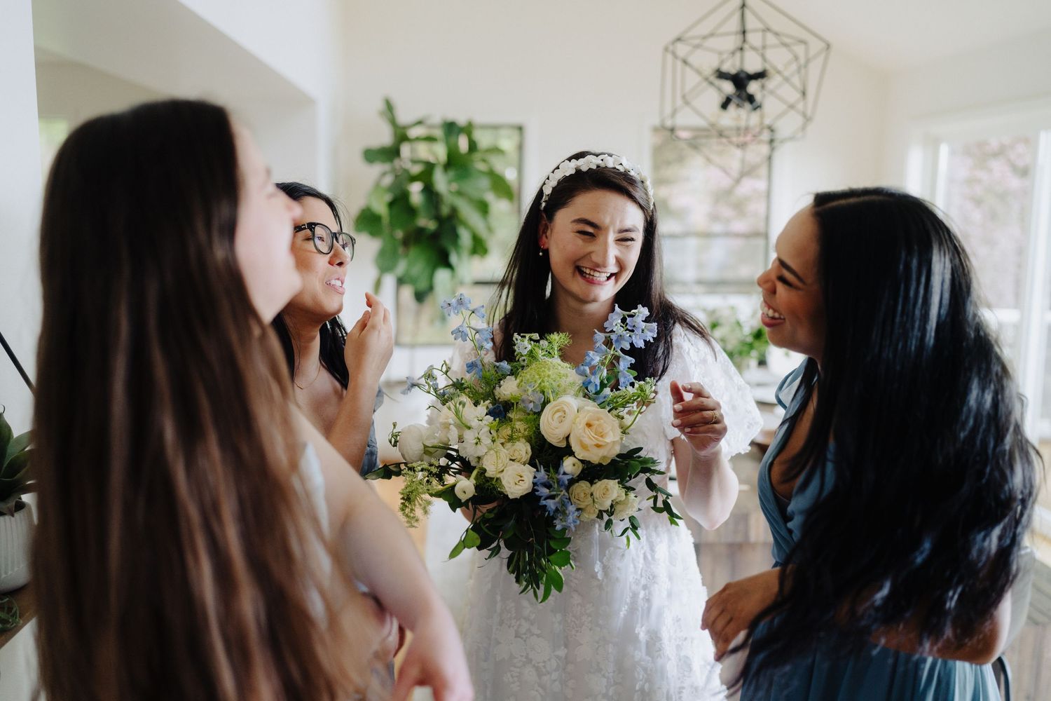 Wedding party gathered indoors with floral arrangements and natural lighting.