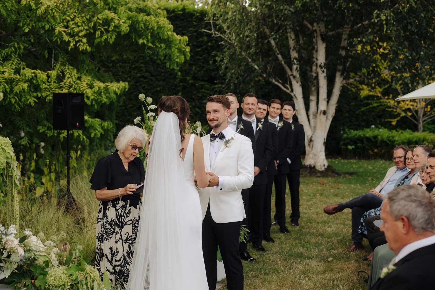 Wedding guests seated in rows during an intimate outdoor garden ceremony.