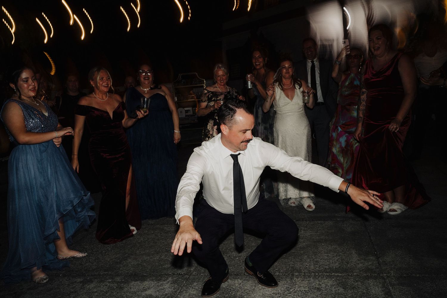 Wedding reception dance party with dramatic lighting and festive atmosphere.