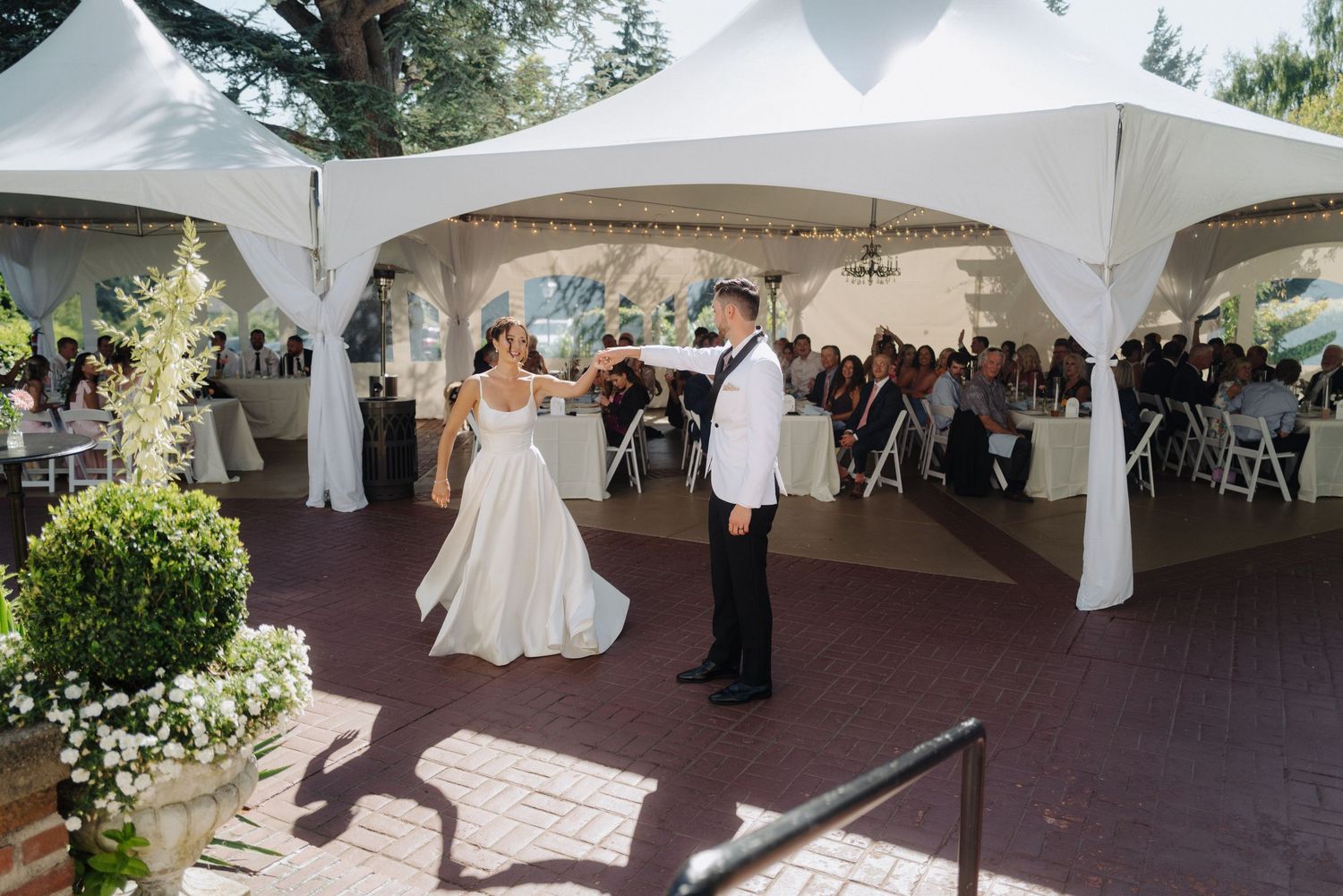 Outdoor wedding reception setup with white tents and elegant table settings.