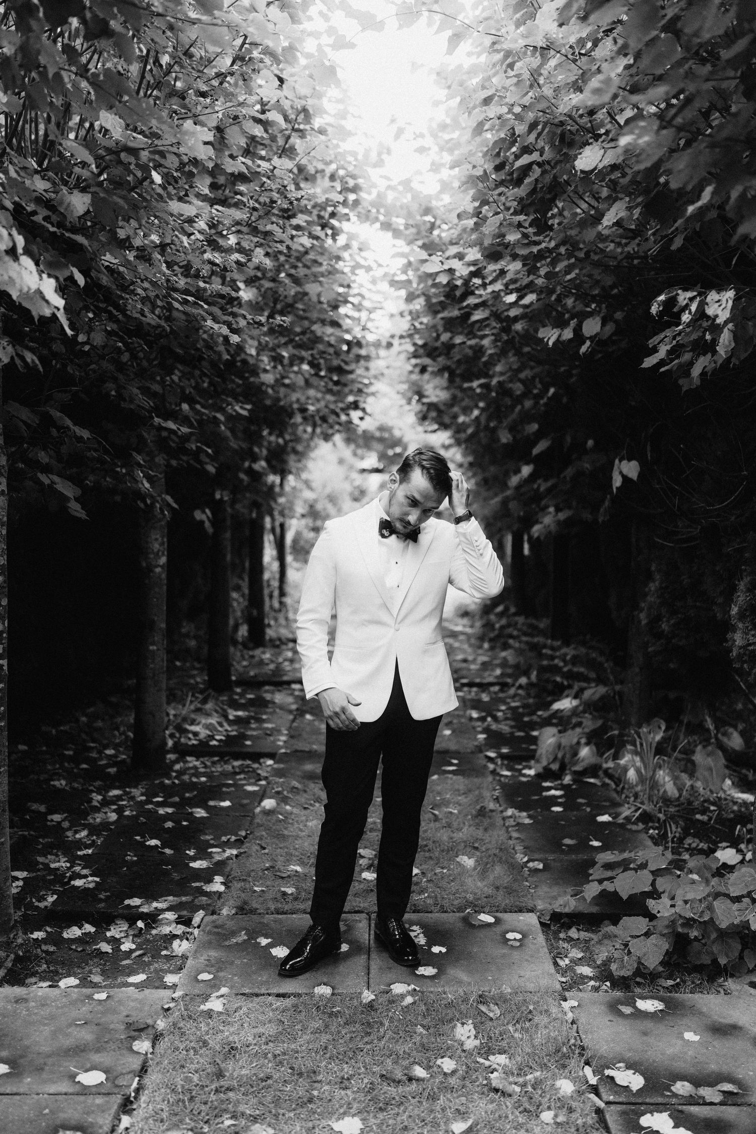 A romantic black and white wedding photo sequence showing a couple in an intimate moment on a tree-lined path.